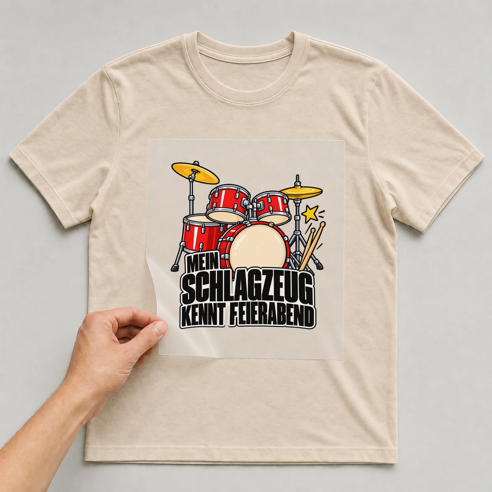 Bügelbild „Mein Schlagzeug kennt Feierabend“ auf beigem T-Shirt, Folie wird aufgelegt