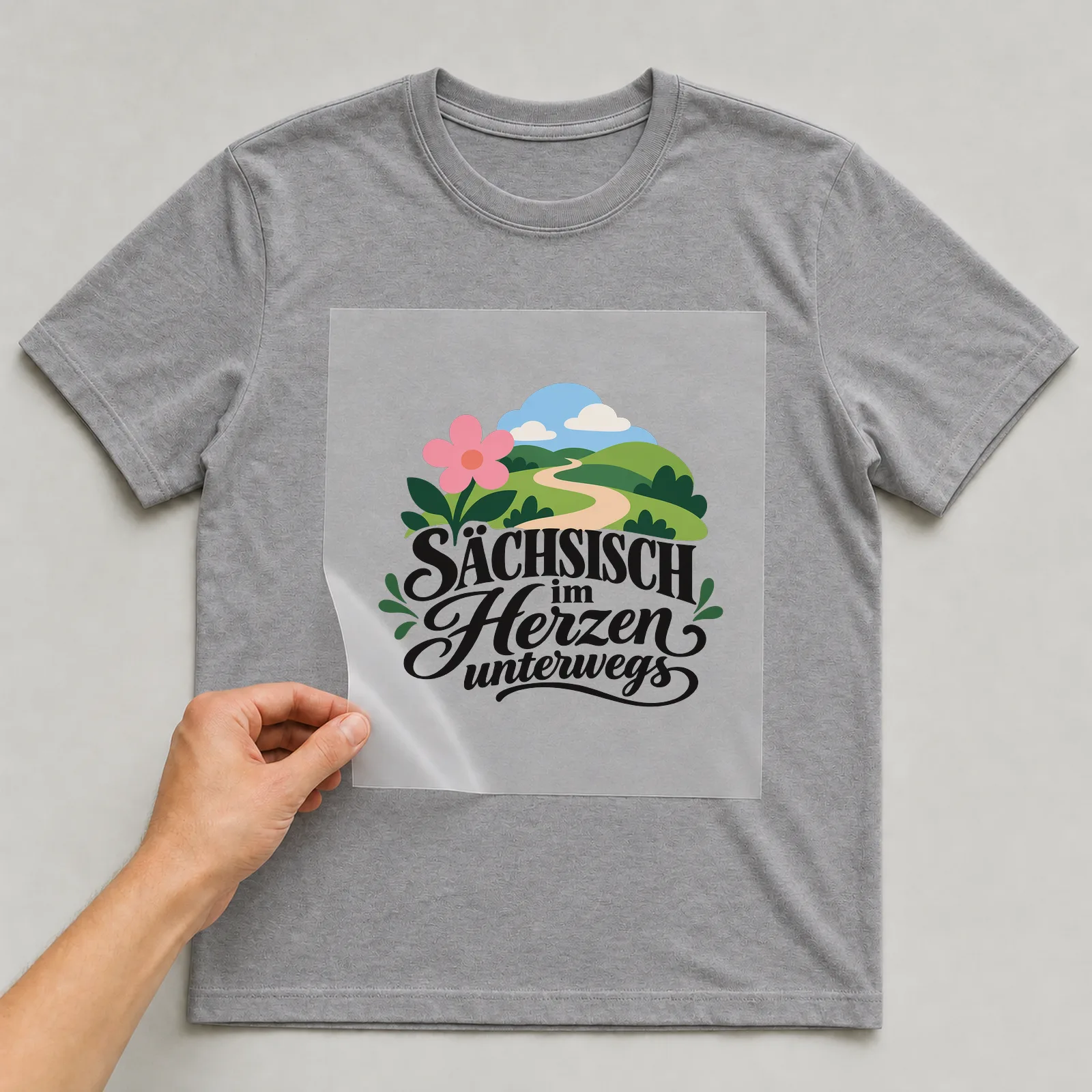 Bügelbild „SÄCHSISCH im Herzen unterwegs“ auf grauem T-Shirt, Folie wird aufgelegt