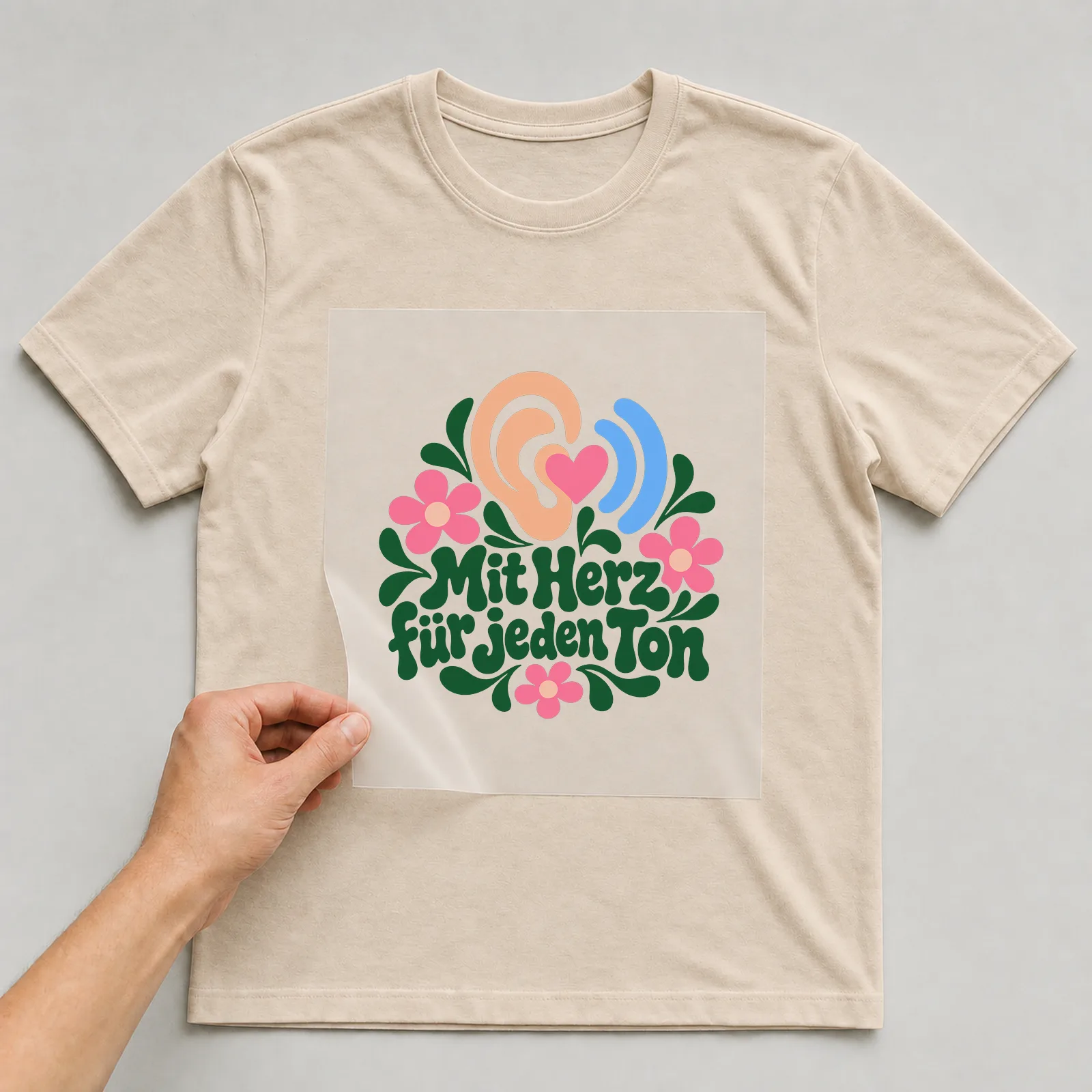 Bügelbild „Mit Herz für jeden Ton“ auf beigem T-Shirt, Folie wird aufgelegt