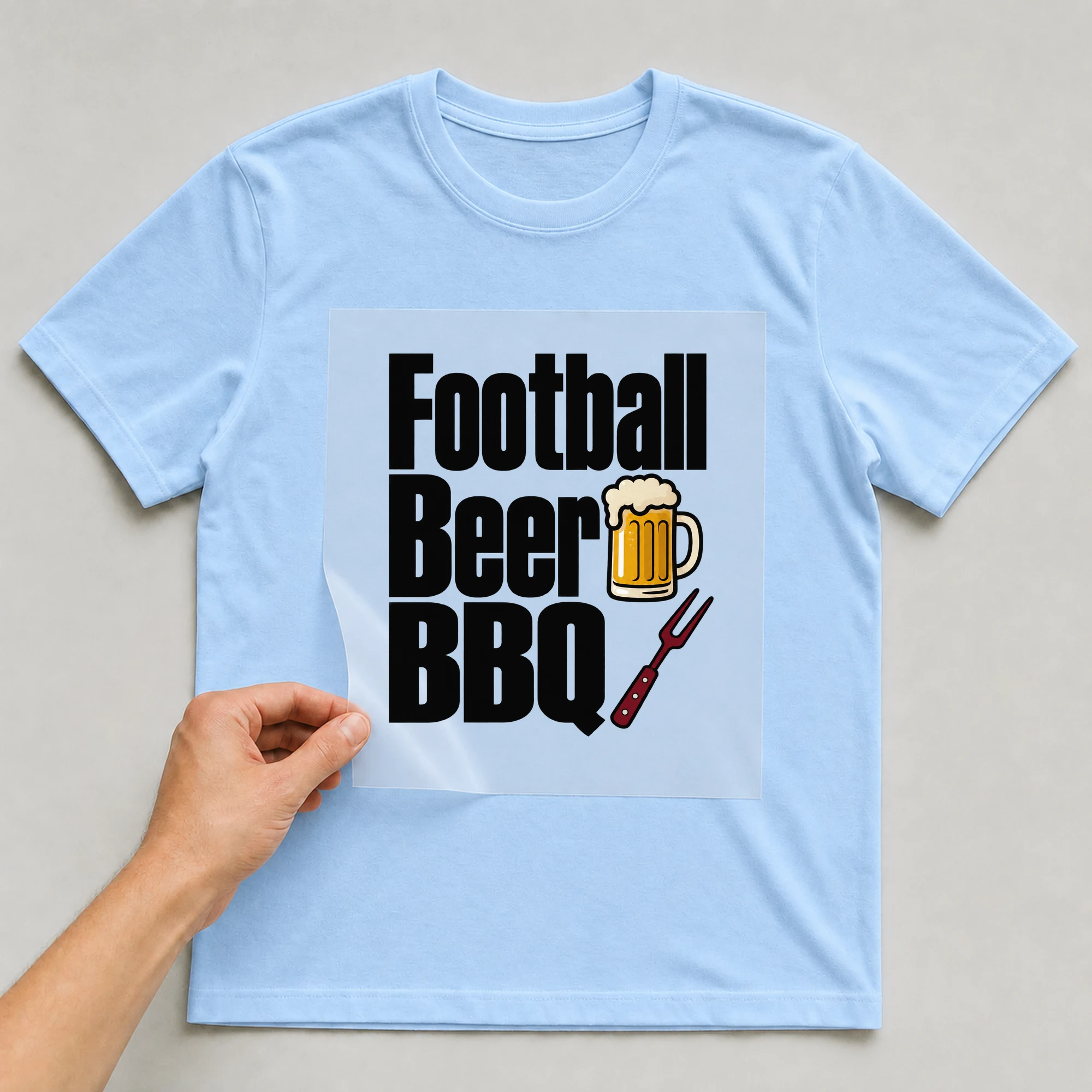 Bügelbild „Football Beer BBQ“ auf babyblauem T-Shirt, Folie wird aufgelegt