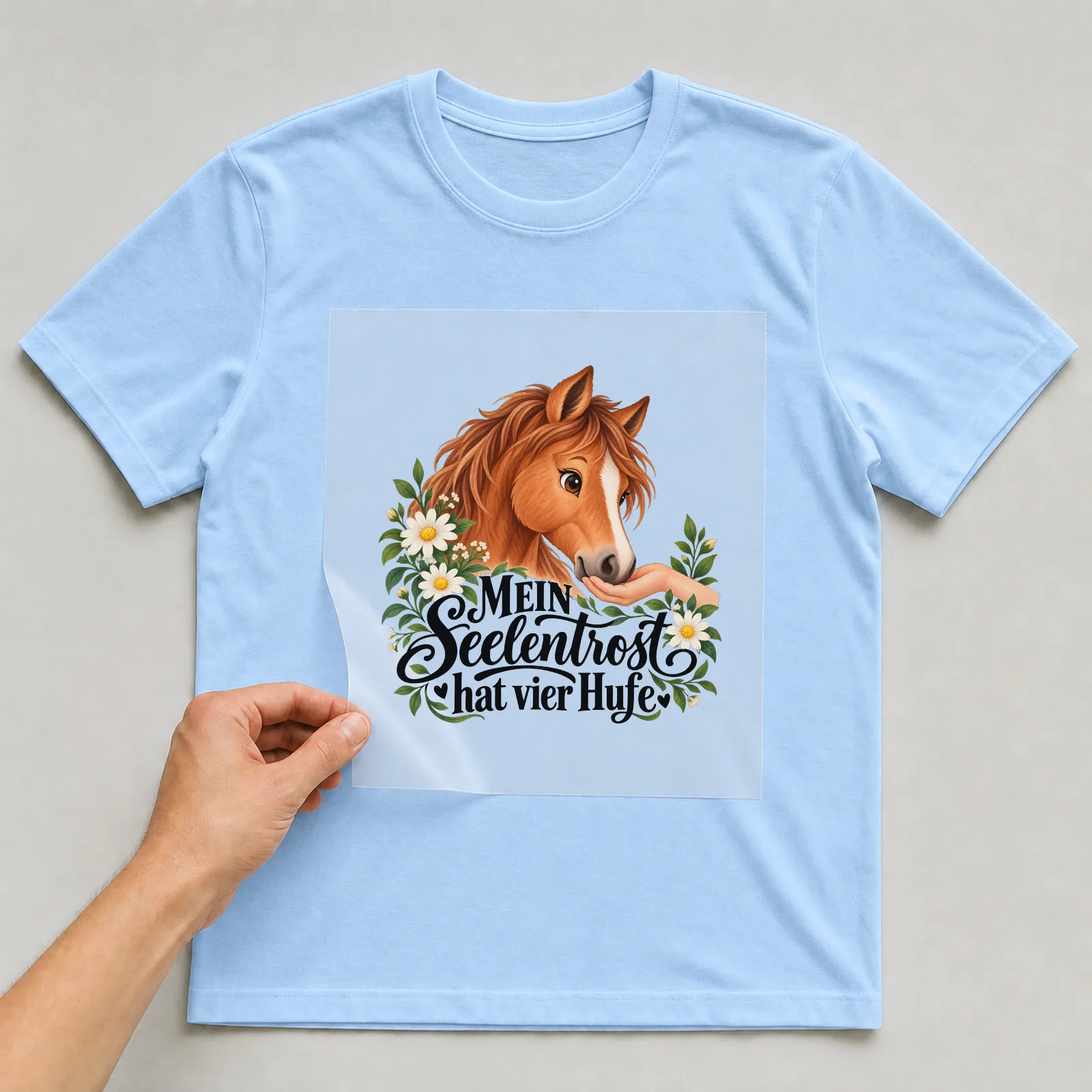 Bügelbild „MEIN Seelentrost hat vier Hufe“ auf hellblauem T-Shirt, Folie wird aufgelegt