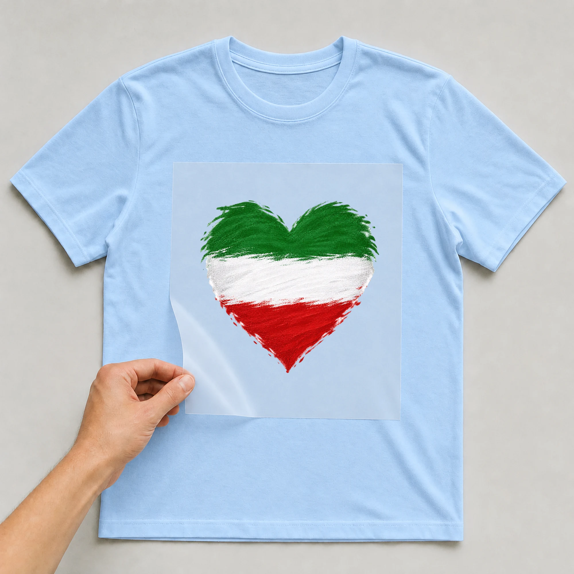 Bügelbild „Herz in Grün Weiß Rot“ auf babyblauem T-Shirt, Folie wird aufgelegt