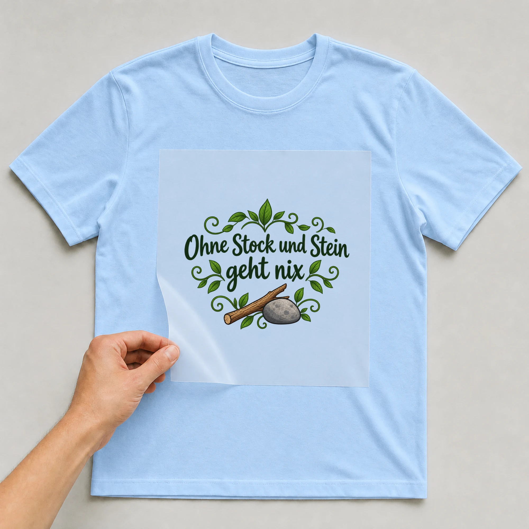 Bügelbild „Ohne Stock und Stein geht nix“ auf babyblauem T-Shirt, Folie wird aufgelegt