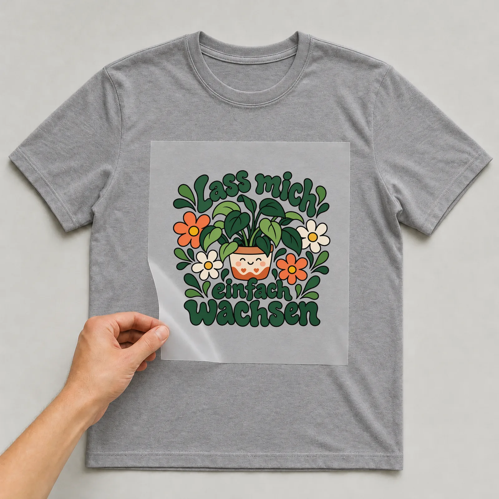Bügelbild „Lass mich einfach wachsen“ auf grauem T-Shirt, Folie wird aufgelegt