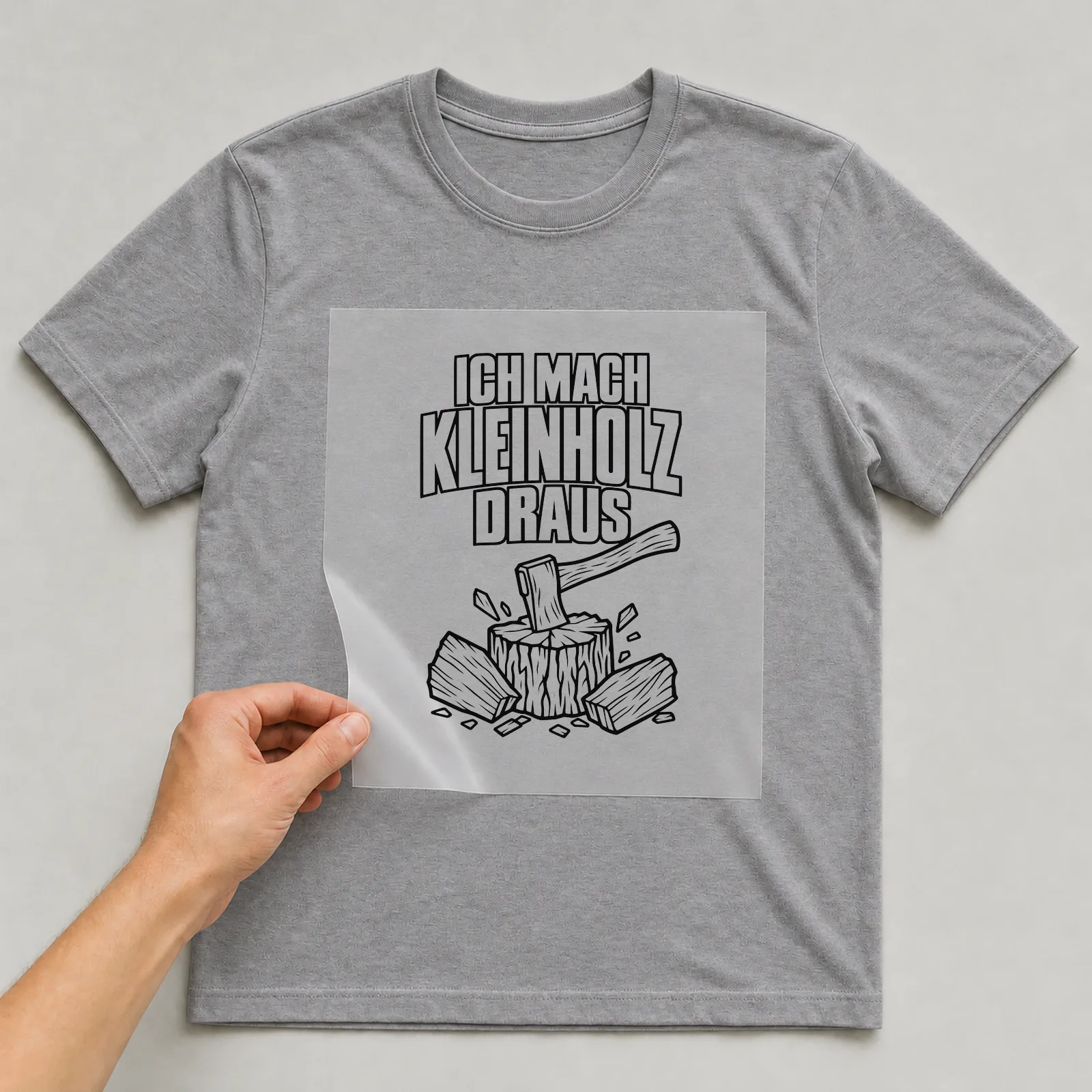 Bügelbild „Ich mach Kleinholz draus“ auf grauem T-Shirt, Folie wird aufgelegt