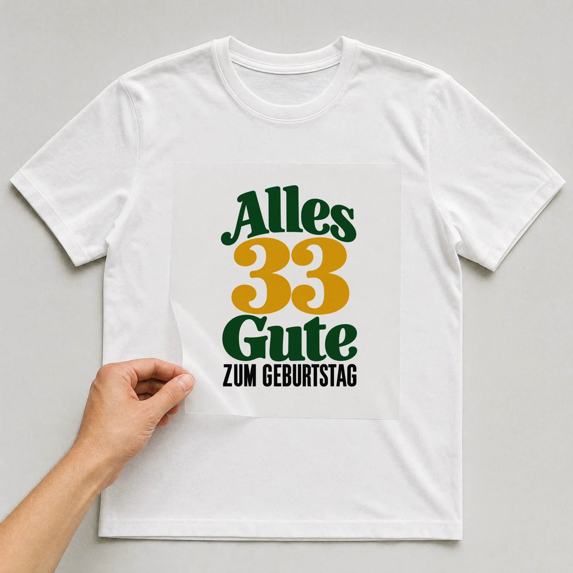 Bügelbild „Alles 33 Gute zum Geburtstag“ auf weißem T-Shirt, Folie wird aufgelegt