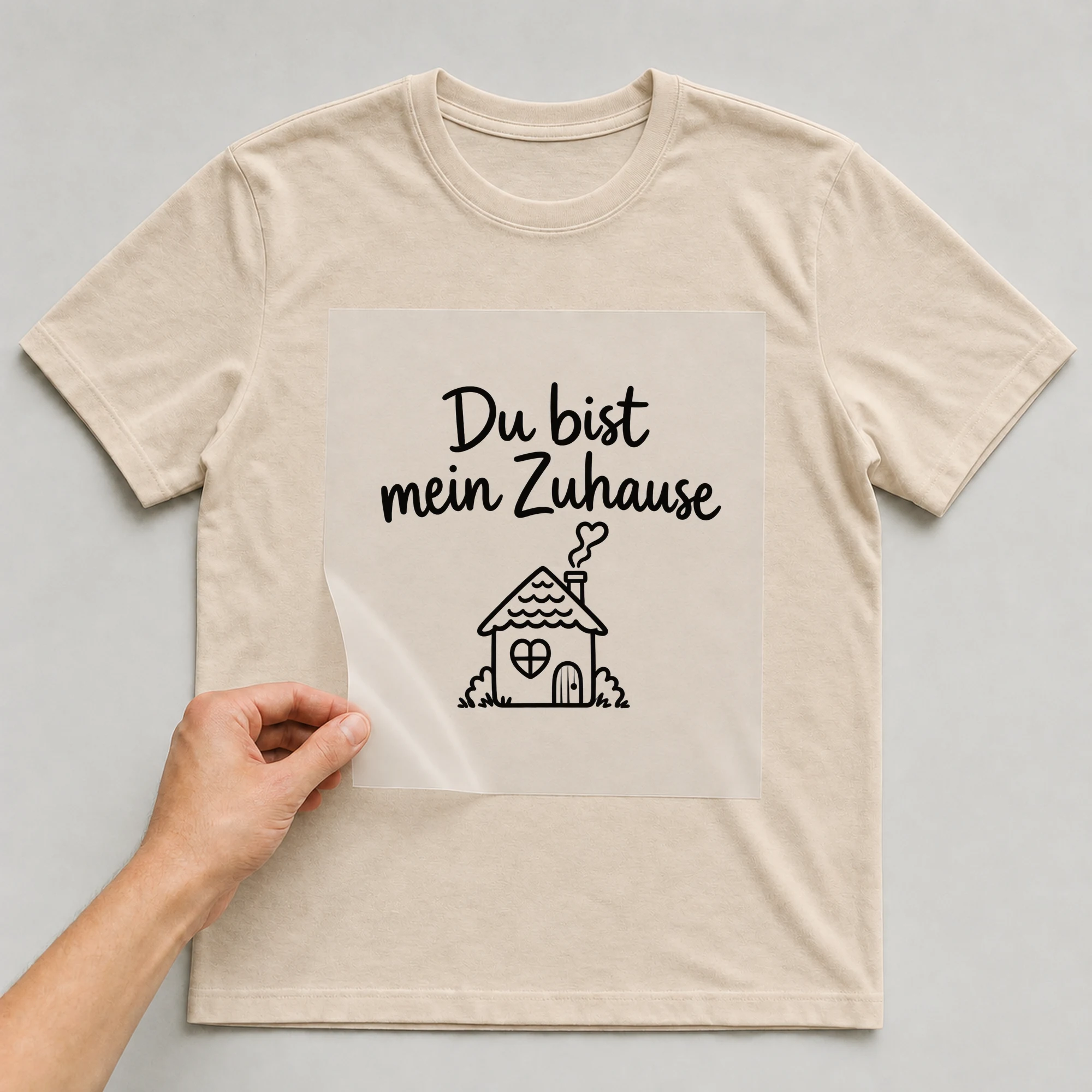 Bügelbild „Du bist mein Zuhause“ auf beigem T-Shirt, Folie wird aufgelegt