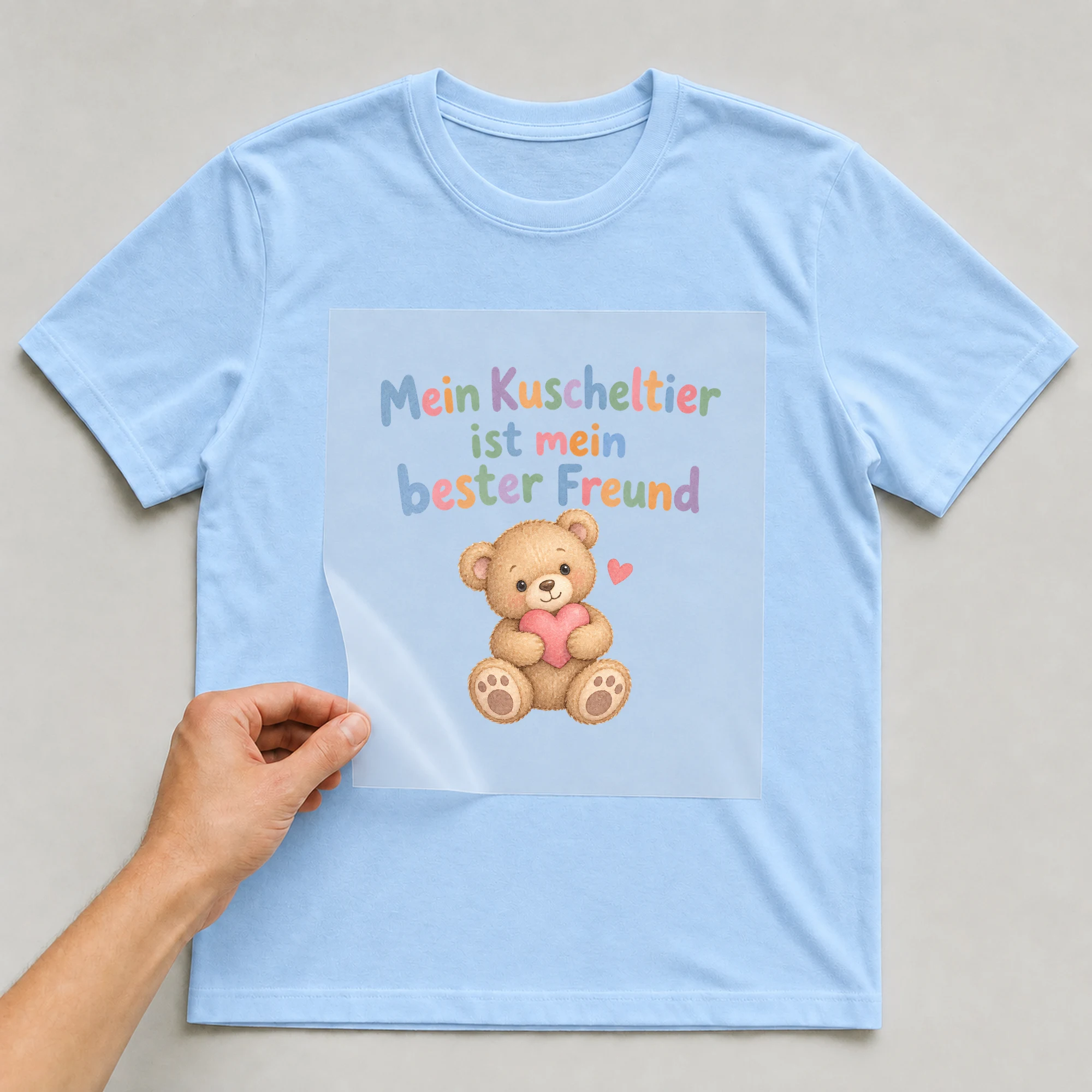 Bügelbild „Mein Kuscheltier ist mein bester Freund“ auf babyblauem T-Shirt, Folie wird aufgelegt