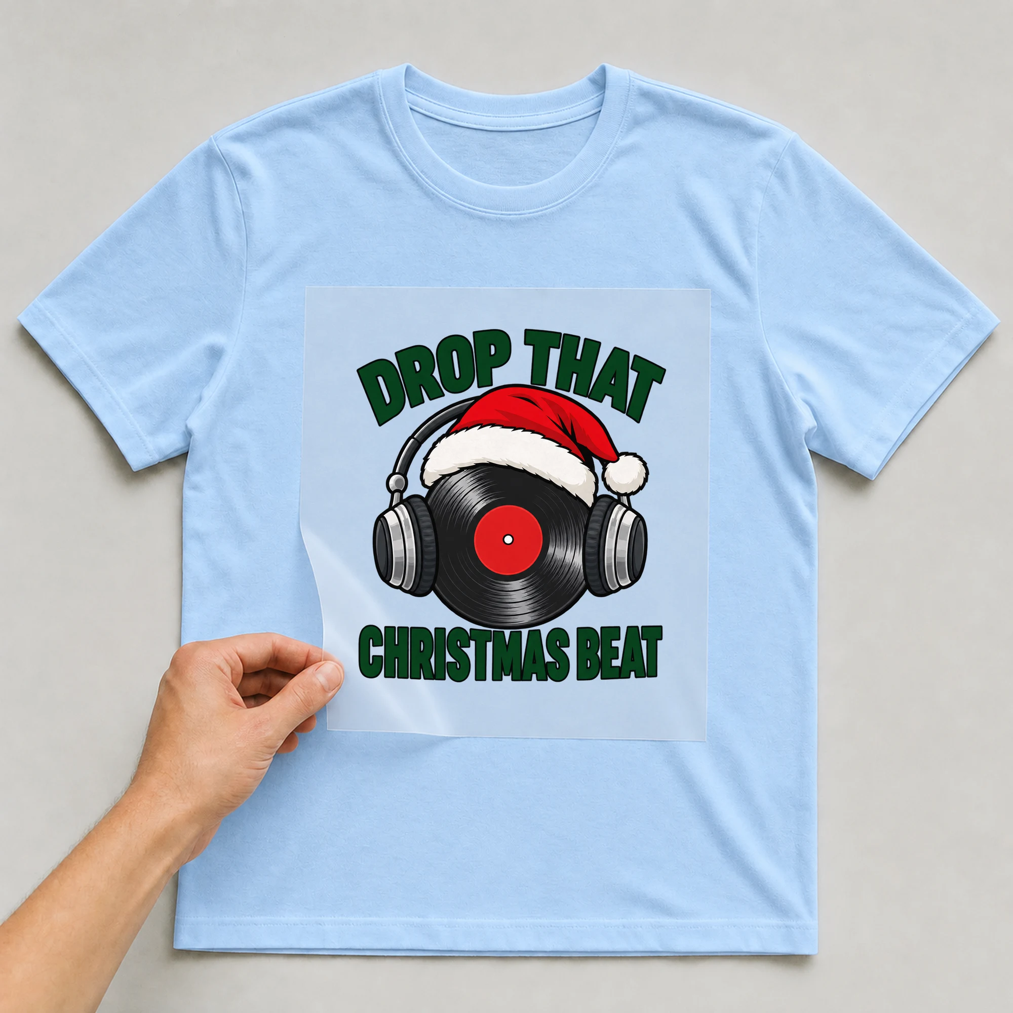 Bügelbild „Drop That Christmas Beat“ auf babyblauem T-Shirt, Folie wird aufgelegt