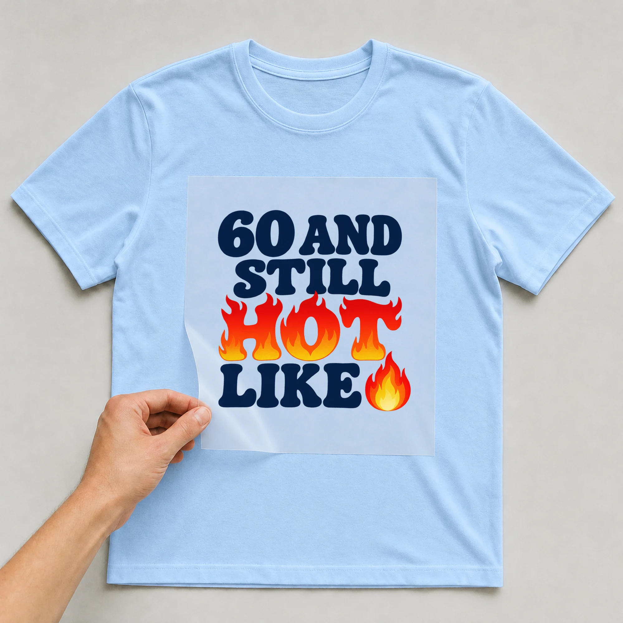 Bügelbild „60 And Still Hot Like“ auf babyblauem T-Shirt, Folie wird aufgelegt
