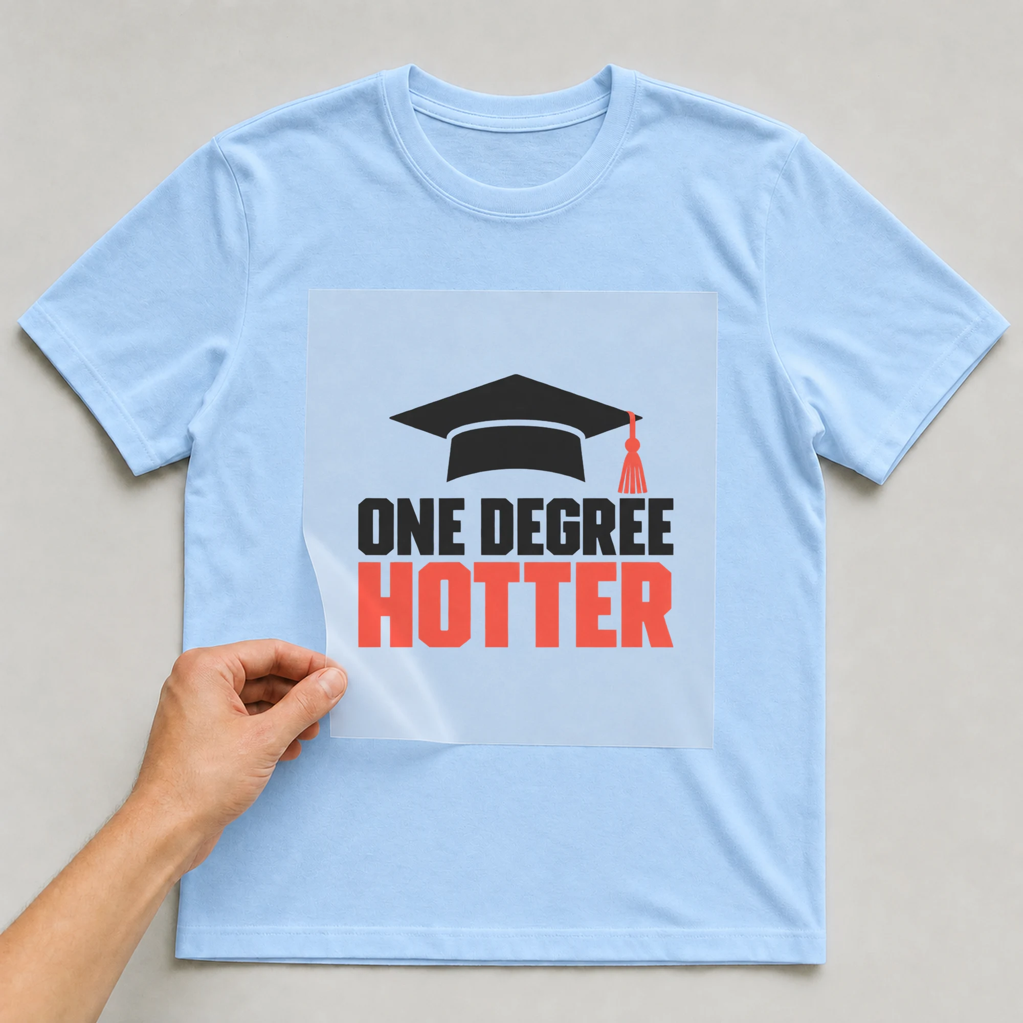 Bügelbild „One Degree Hotter“ auf babyblauem T-Shirt, Folie wird aufgelegt