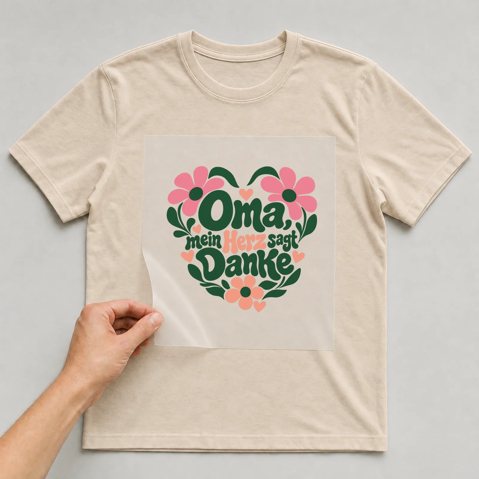 Bügelbild „Oma, mein Herz sagt Danke“ auf beigem T-Shirt, Folie wird aufgelegt