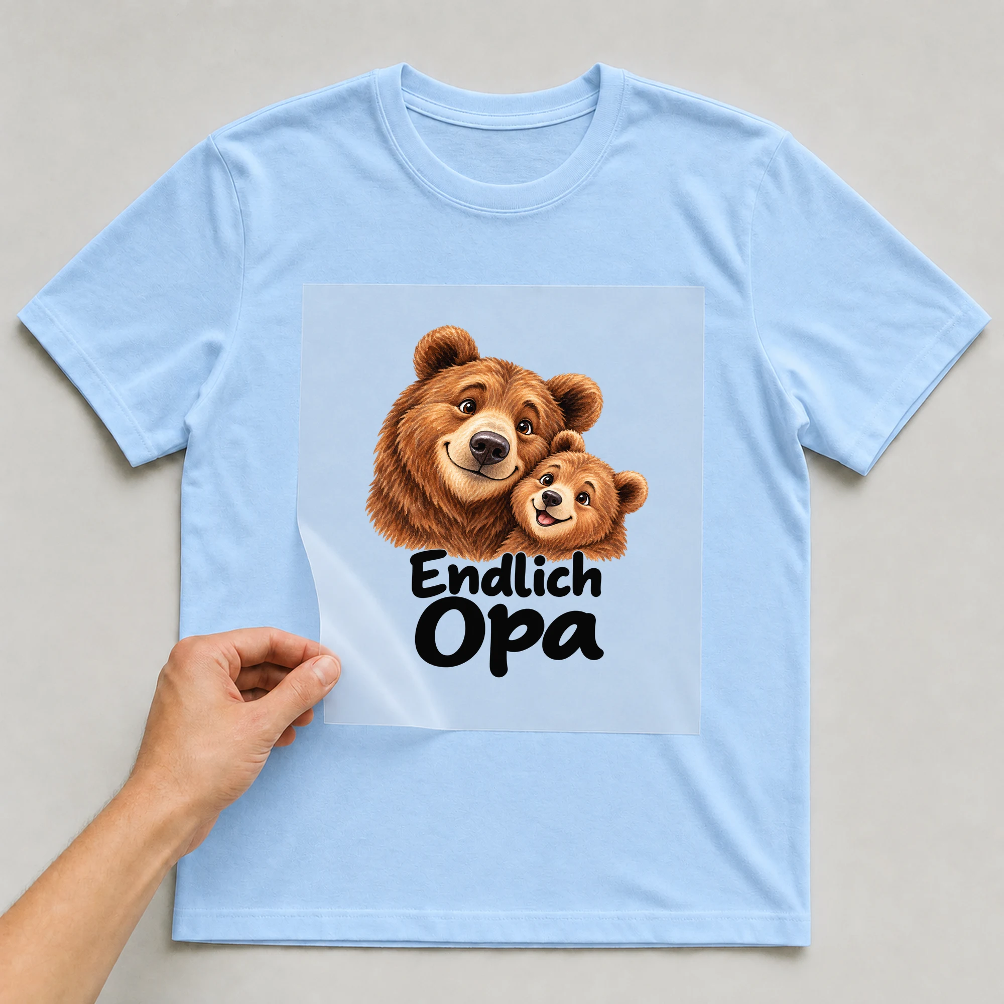 Bügelbild „Endlich Opa“ auf babyblauem T-Shirt, Folie wird aufgelegt