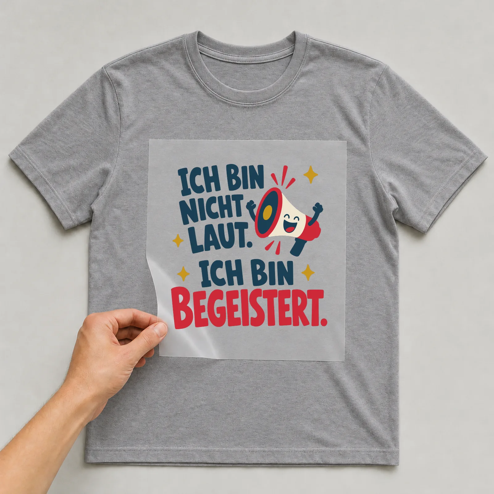 Bügelbild Ich bin nicht laut. Ich bin begeistert. auf grauem T-Shirt, Folie wird aufgelegt