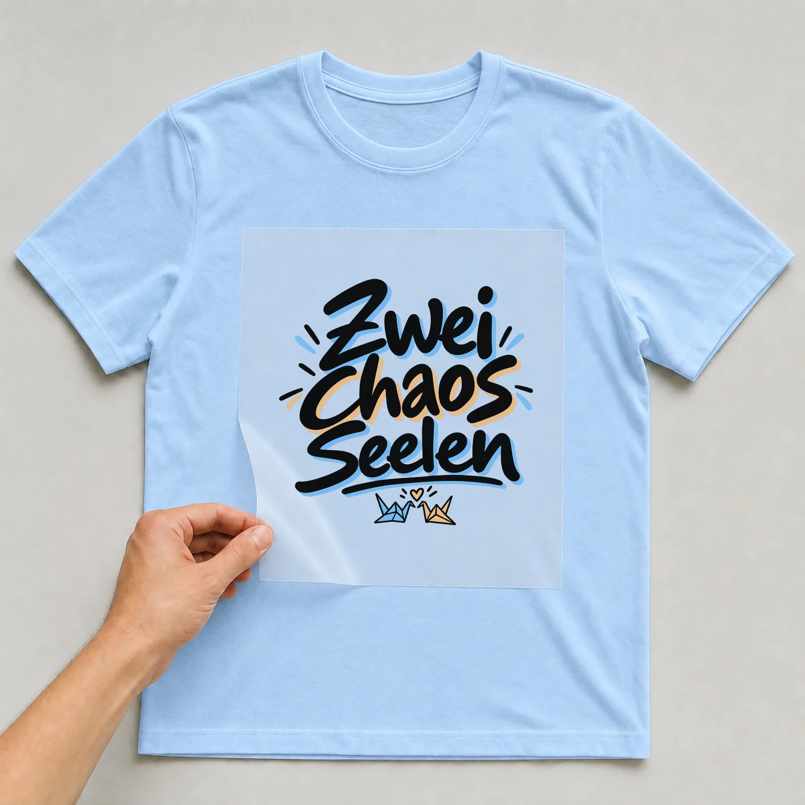 Bügelbild „Zwei Chaos Seelen“ auf hellblauem T-Shirt, Folie wird aufgelegt