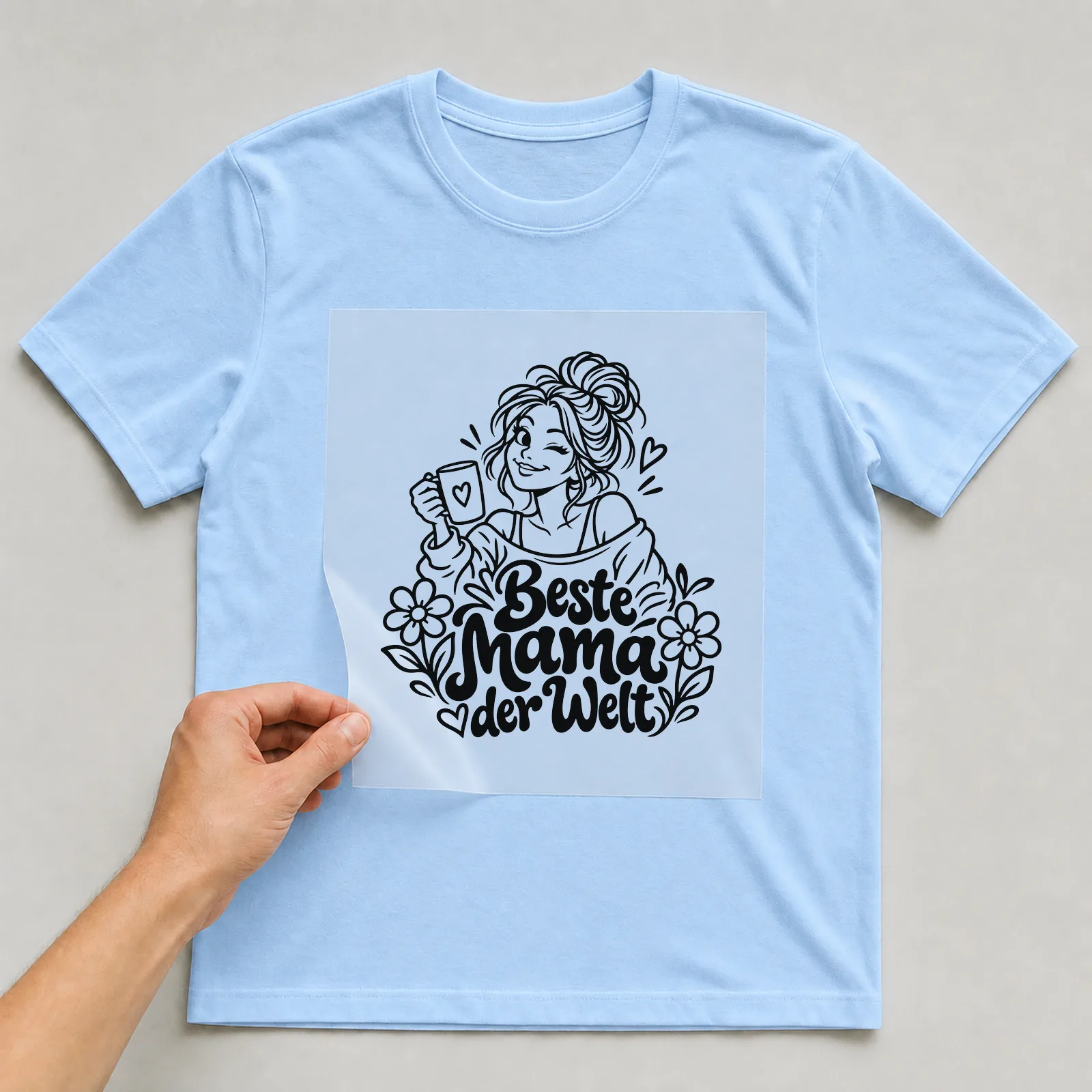 Bügelbild „Beste Mama der Welt“ auf hellblauem T-Shirt, Folie wird aufgelegt