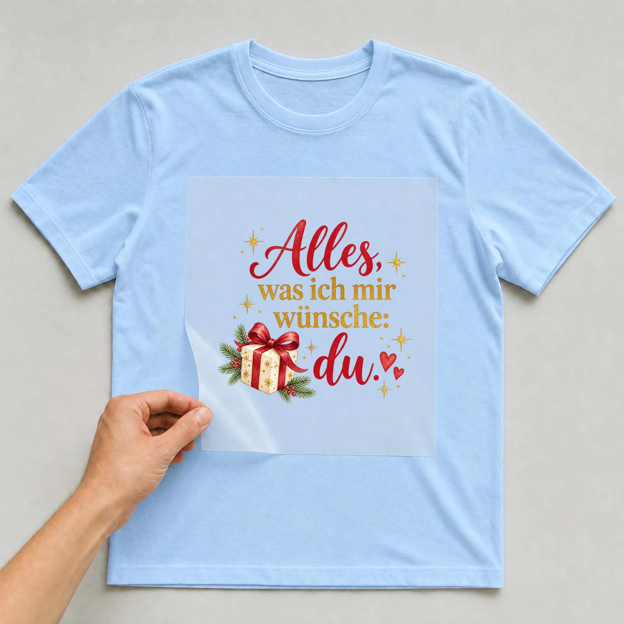 Bügelbild „Alles, was ich mir wünsche: du.“ auf babyblauem T-Shirt, Folie wird aufgelegt