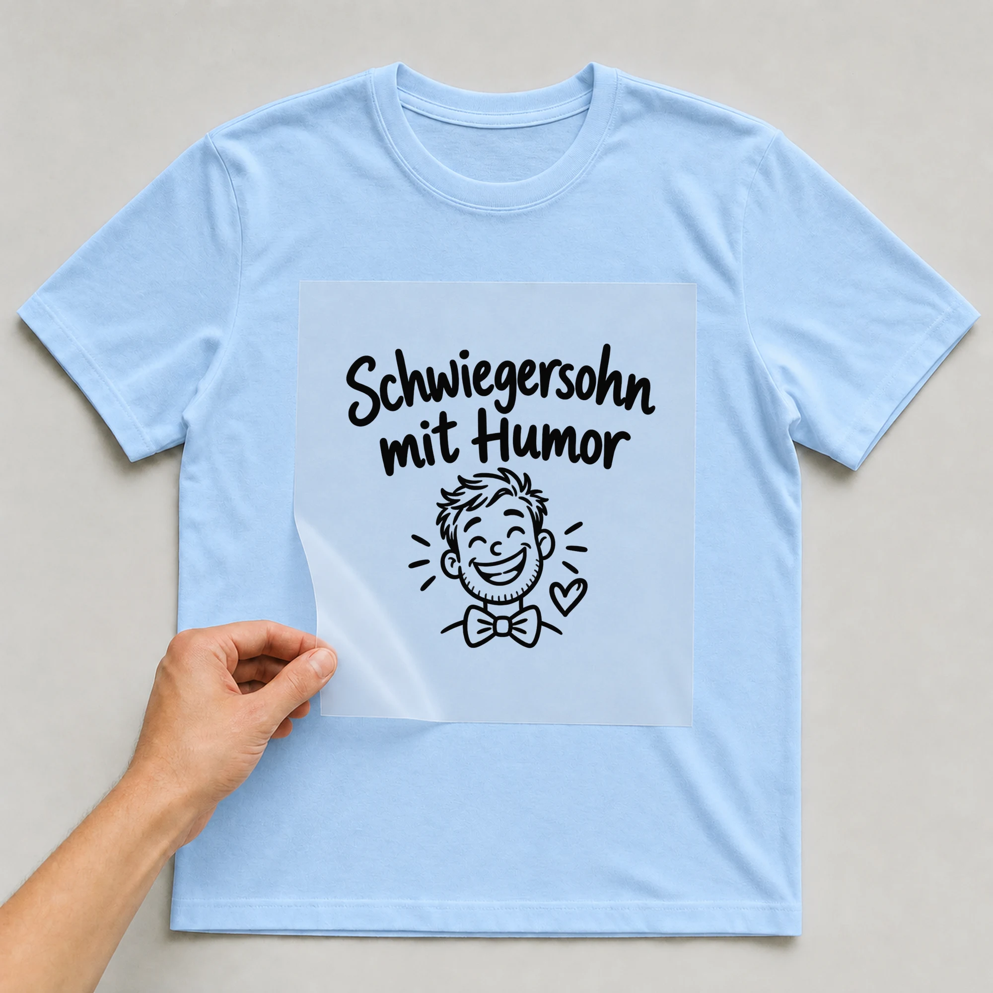 Bügelbild „Schwiegersohn mit Humor“ auf babyblauem T-Shirt, Folie wird aufgelegt