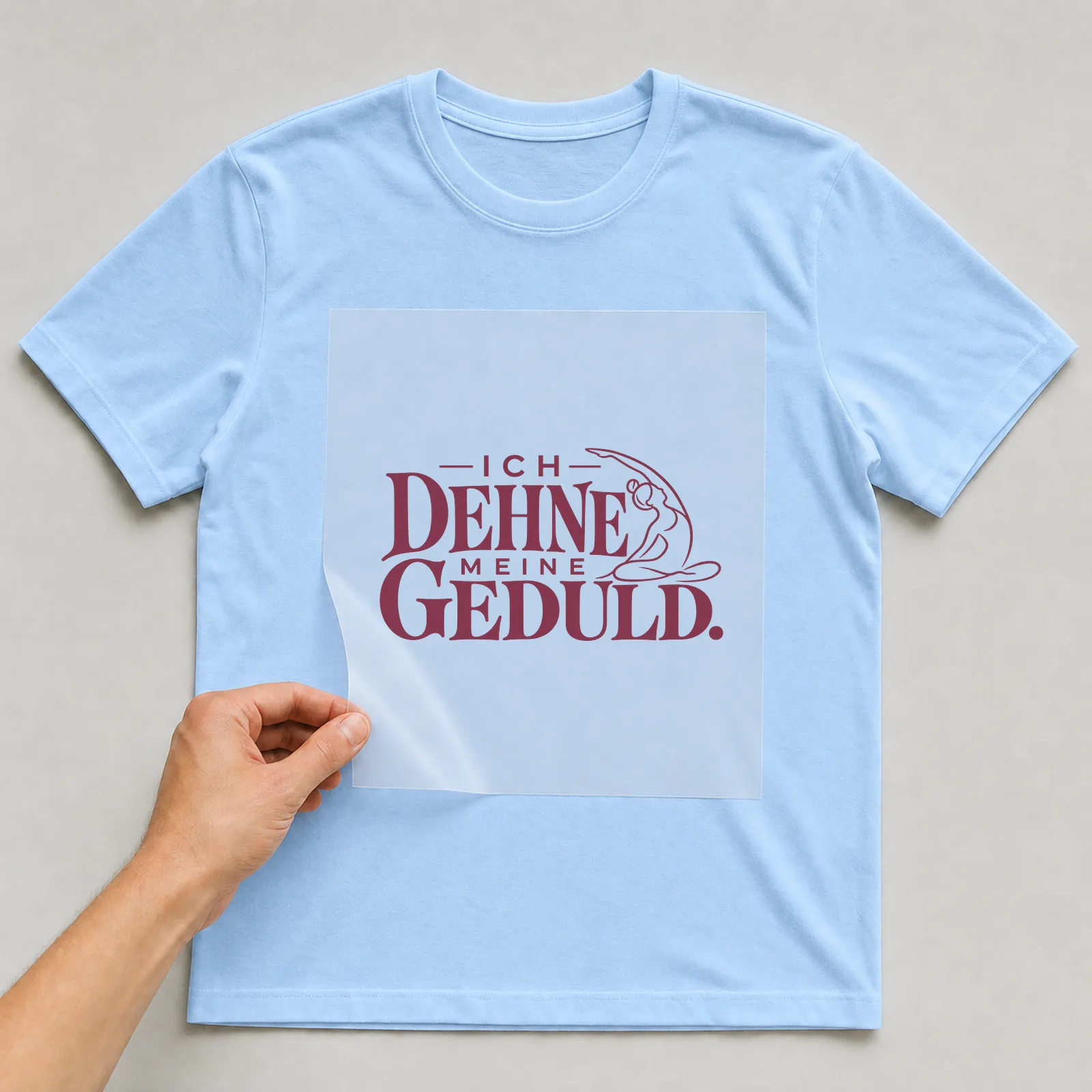 Bügelbild „Ich dehne meine Geduld“ auf hellblauem T-Shirt, Folie wird aufgelegt