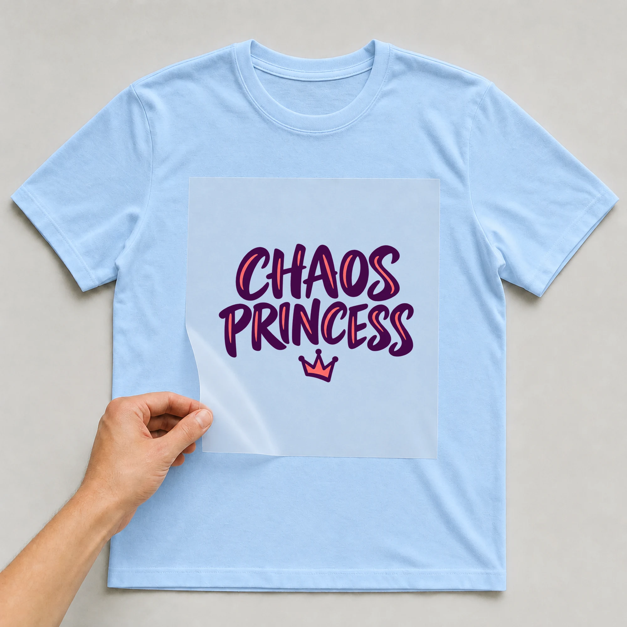 Bügelbild „Chaos Princess“ auf babyblauem T-Shirt, Folie wird aufgelegt
