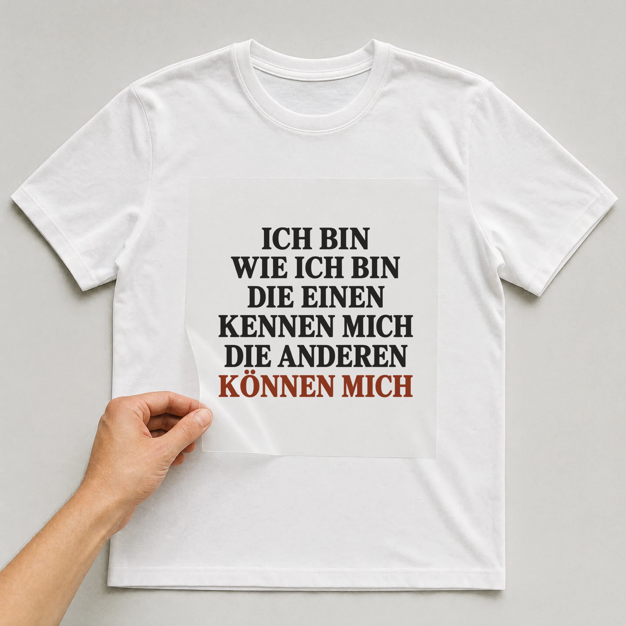 Bügelbild „Ich bin wie ich bin die einen kennen mich die anderen können mich“ auf weißem T-Shirt, Folie wird aufgelegt