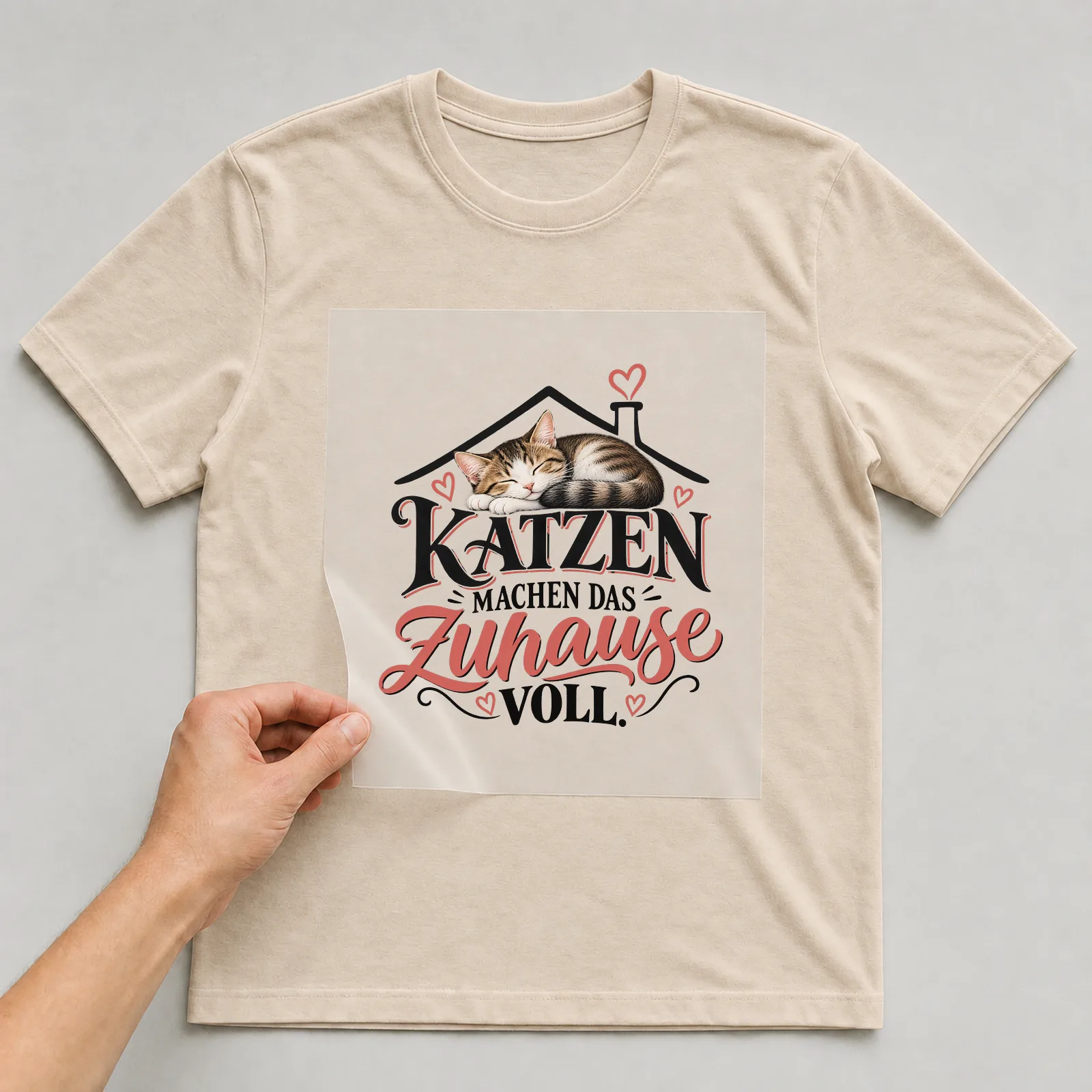 Bügelbild „Katzen machen das zuhause voll“ auf beigem T-Shirt, Folie wird aufgelegt