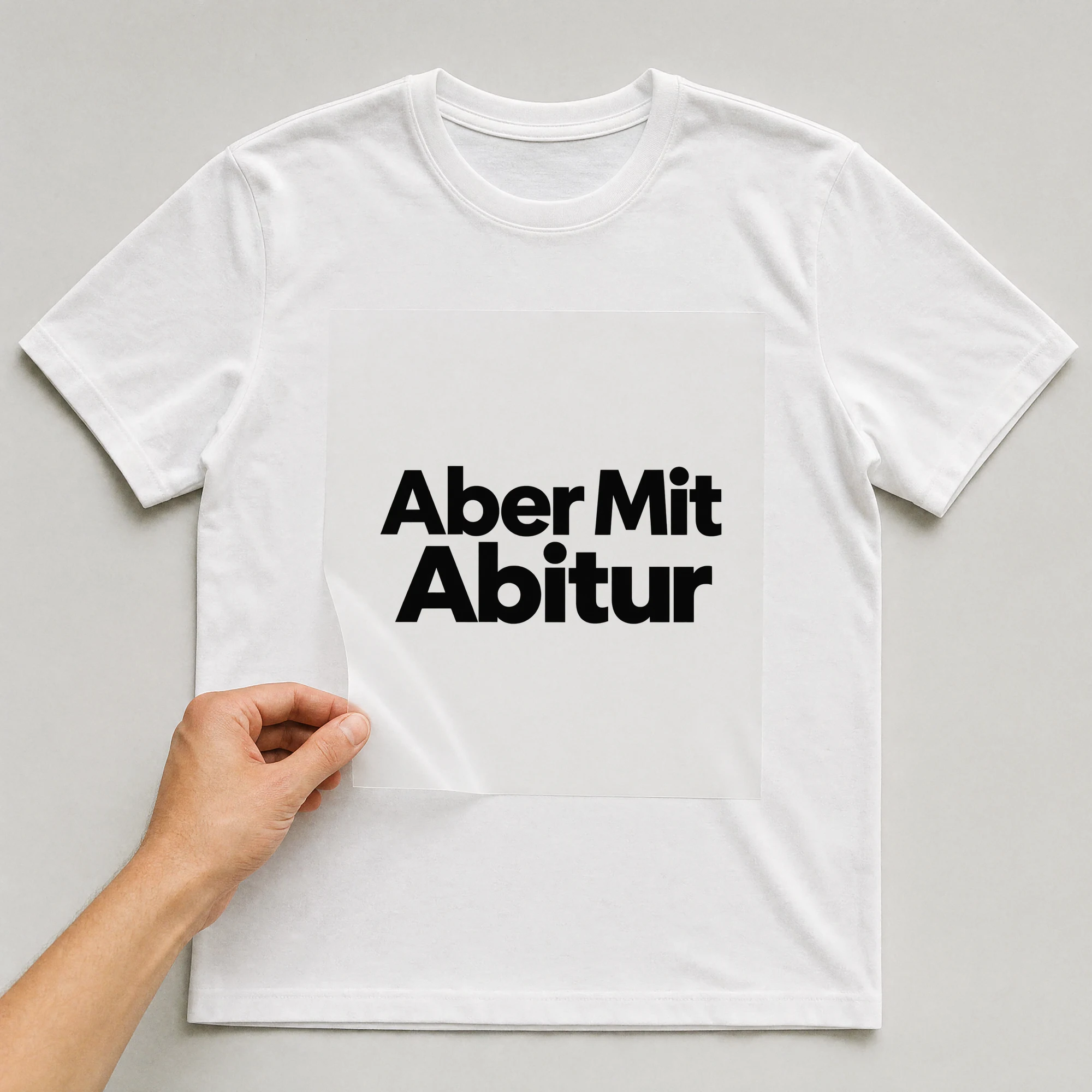 Bügelbild „Aber Mit Abitur“ auf weißem T-Shirt, Folie wird aufgelegt