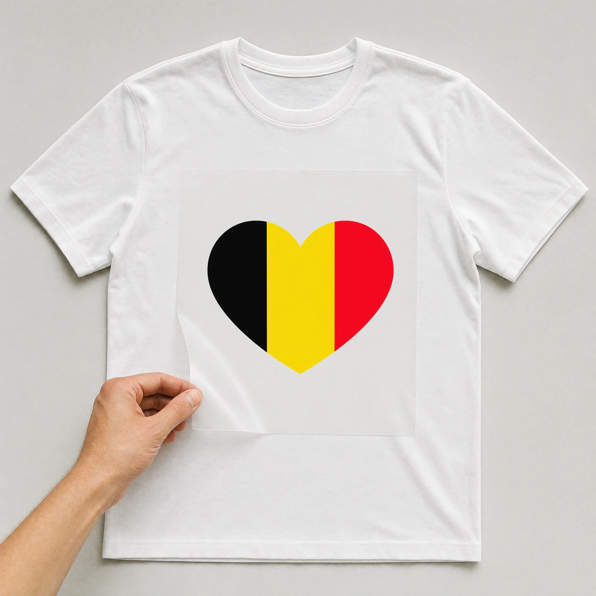 Bügelbild „Länder Flagge Belgien“ auf weißem T-Shirt, Folie wird aufgelegt