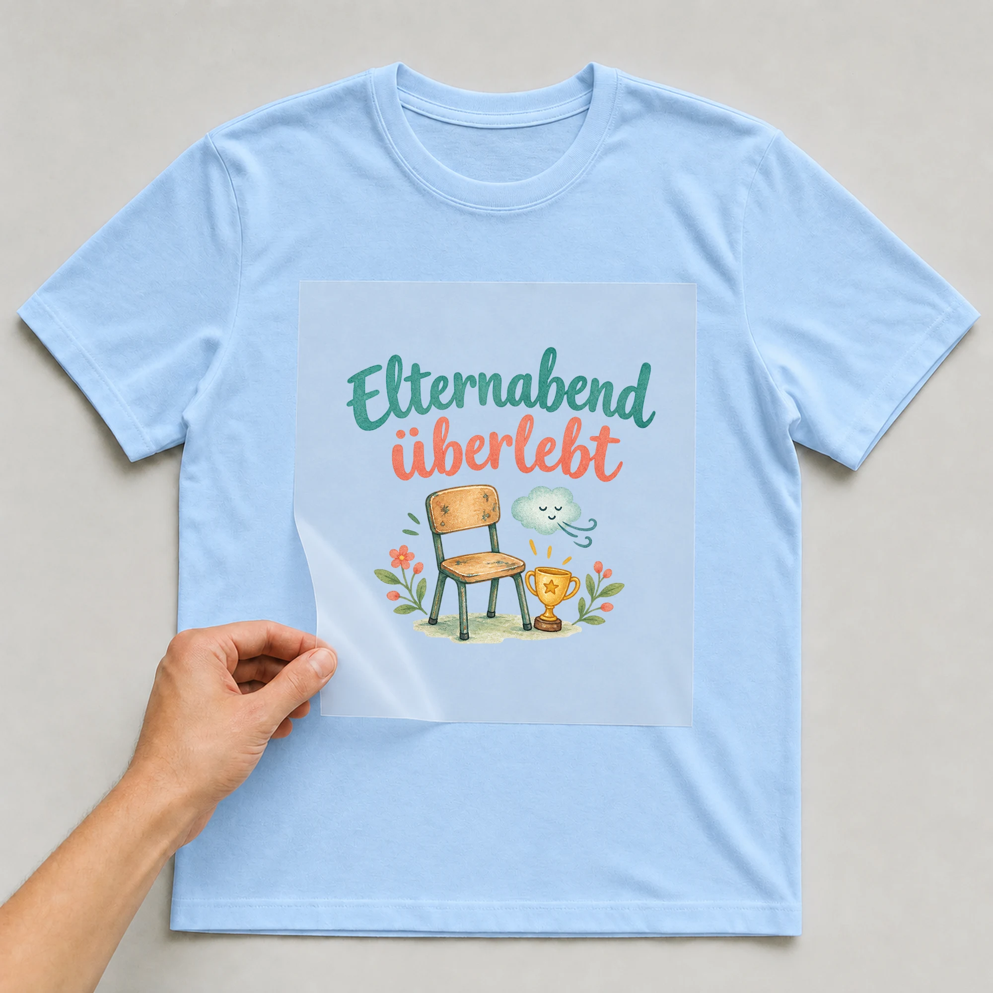 Bügelbild „Elternabend überlebt“ auf babyblauem T-Shirt, Folie wird aufgelegt