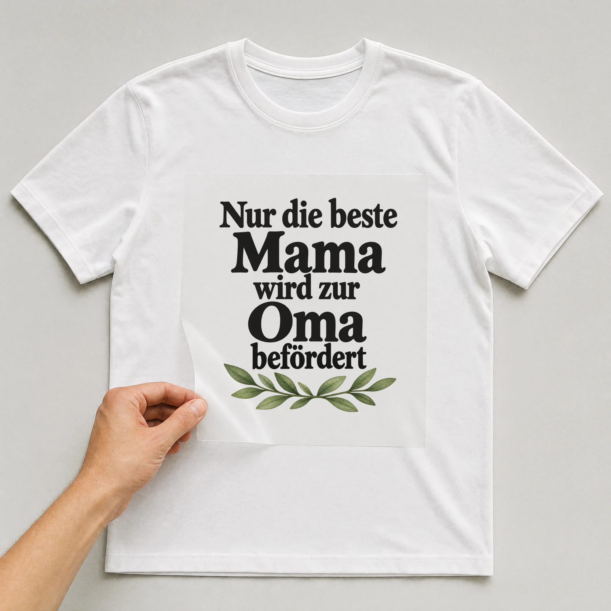 Bügelbild „Nur die beste Mama wird zur Oma befördert“ auf weißem T-Shirt, Folie wird aufgelegt