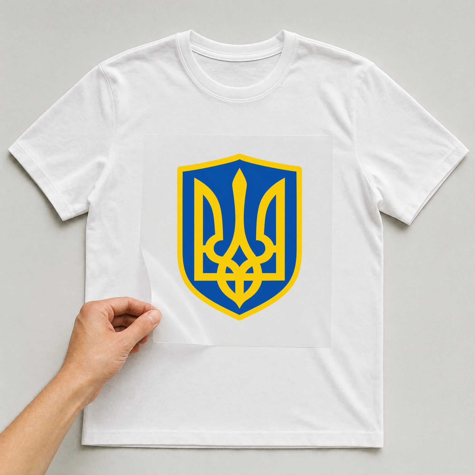 Bügelbild „Ukraine Wappen“ auf weißem T-Shirt, Folie wird aufgelegt