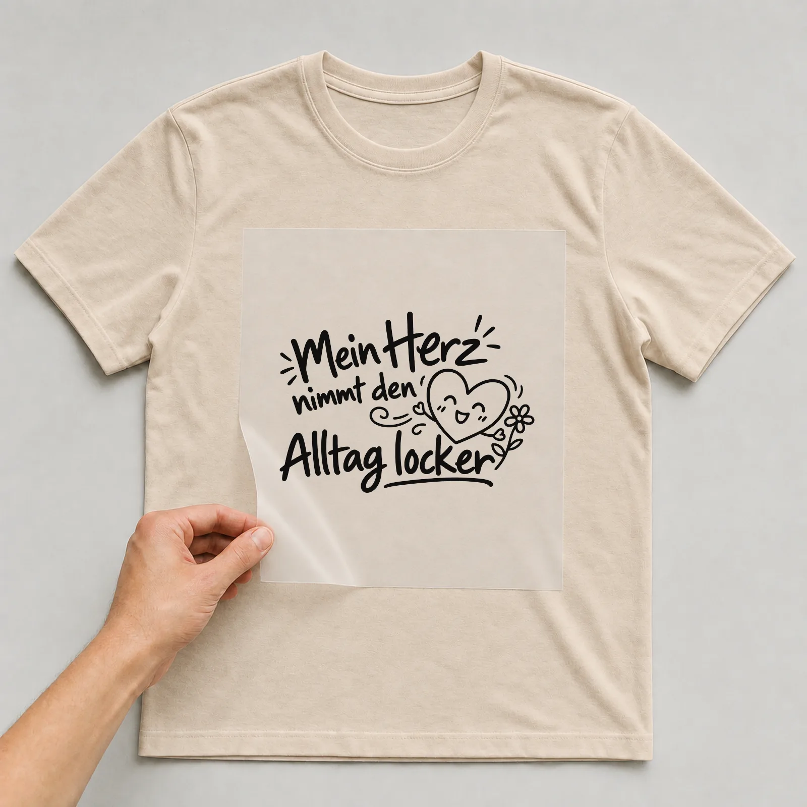 Bügelbild „Mein Herz nimmt den Alltag locker“ auf beigem T-Shirt, Folie wird aufgelegt