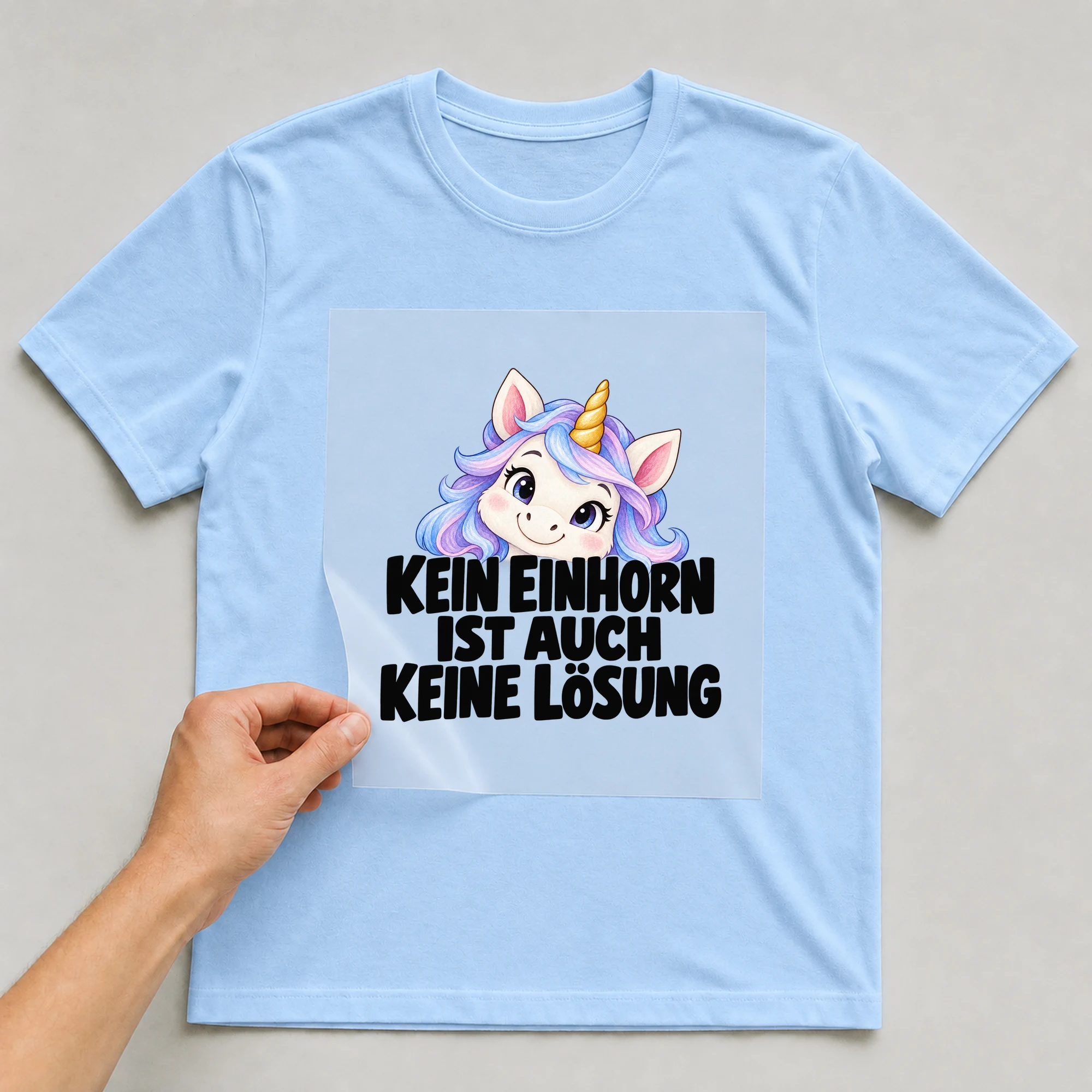 Bügelbild „Kein Einhorn Ist Auch Keine Lösung“ auf babyblauem T-Shirt, Folie wird aufgelegt