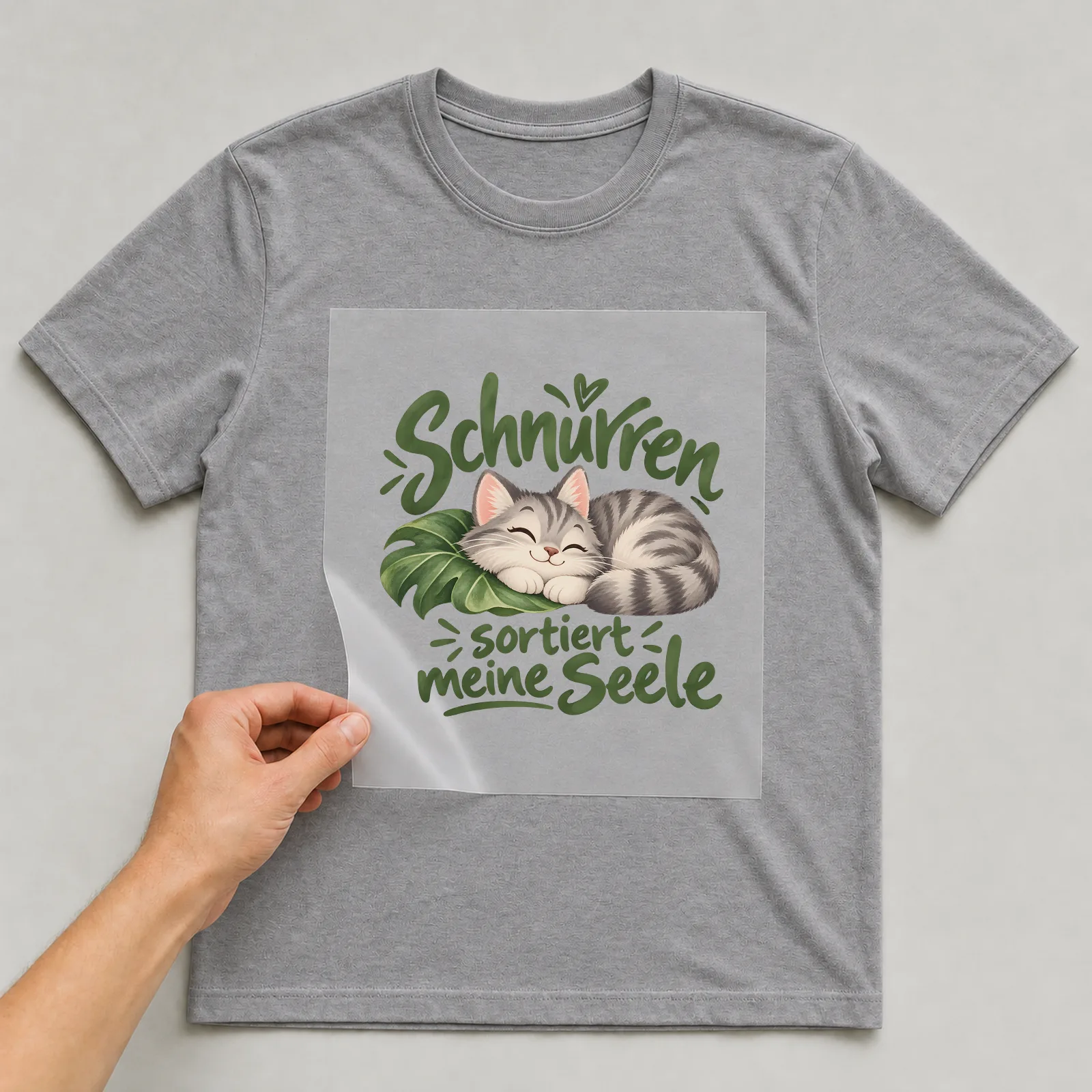 Bügelbild „Schnurren sortiert meine Seele“ auf grauem T-Shirt, Folie wird aufgelegt