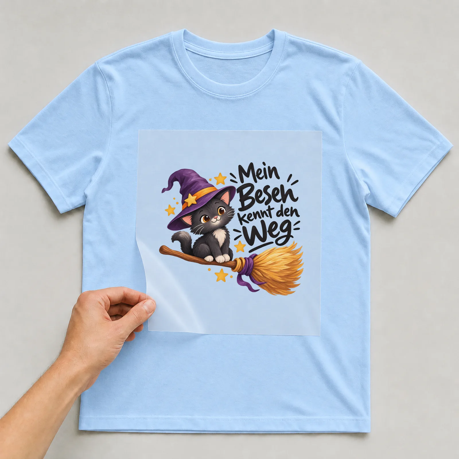 Bügelbild „Mein Besen kennt den Weg“ auf hellblauem T-Shirt, Folie wird aufgelegt