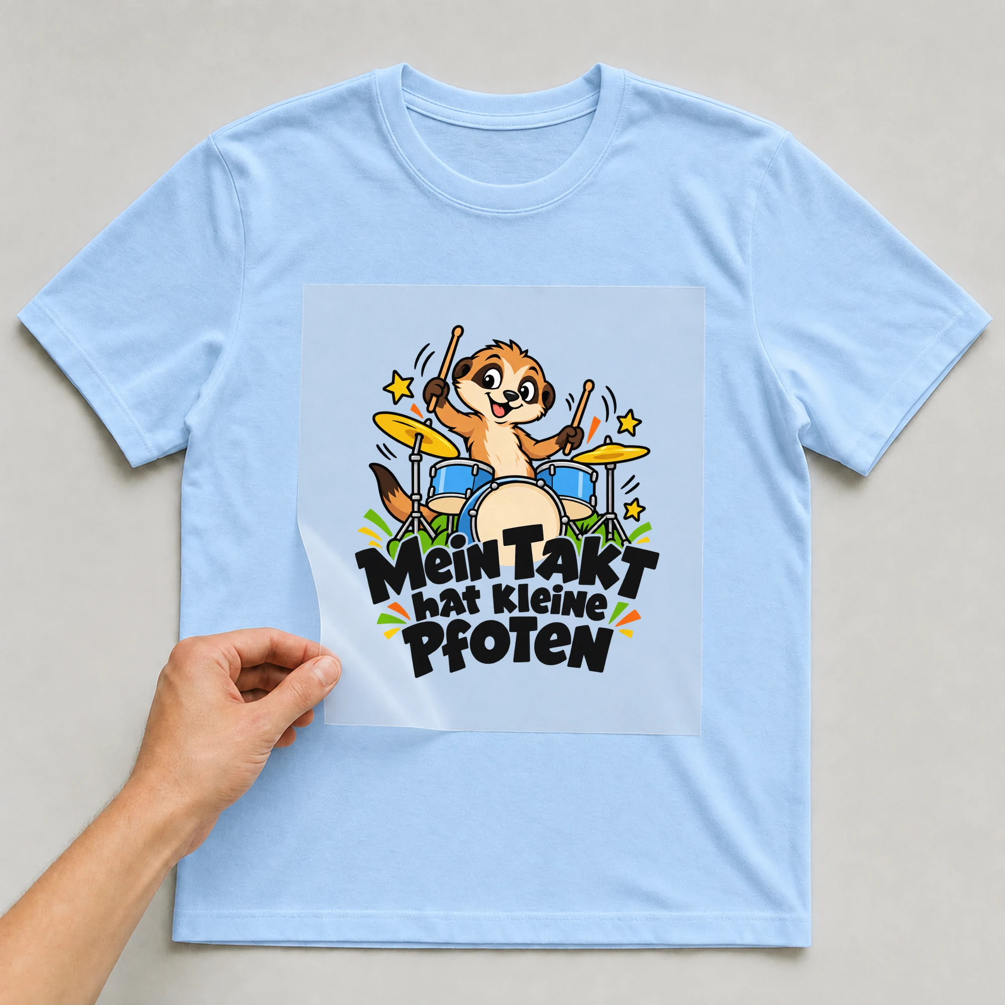 Bügelbild „Mein Takt hat kleine Pfoten“ auf hellblauem T-Shirt, Folie wird aufgelegt