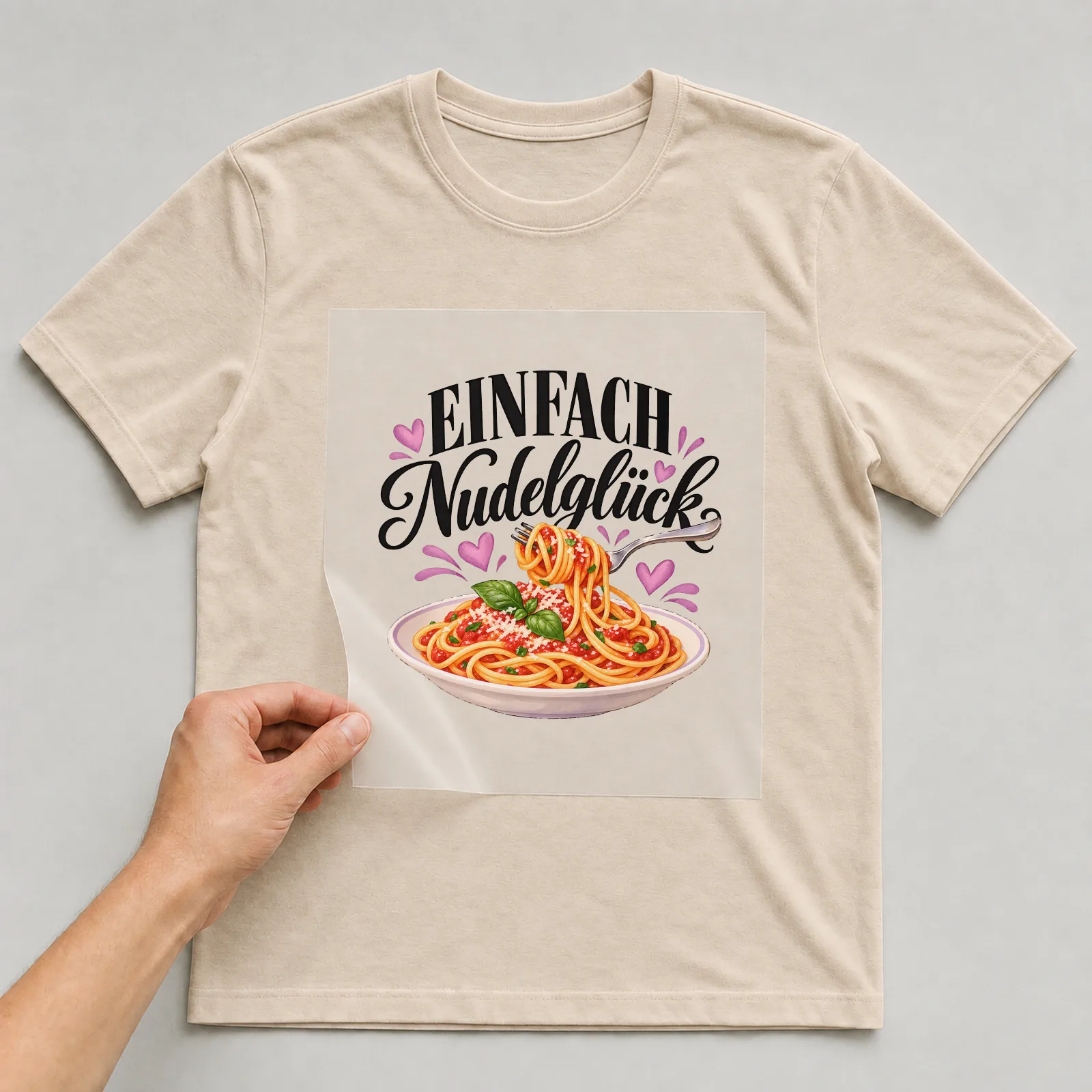 Bügelbild „Einfach Nudelglück“ auf beigem T-Shirt, Folie wird aufgelegt