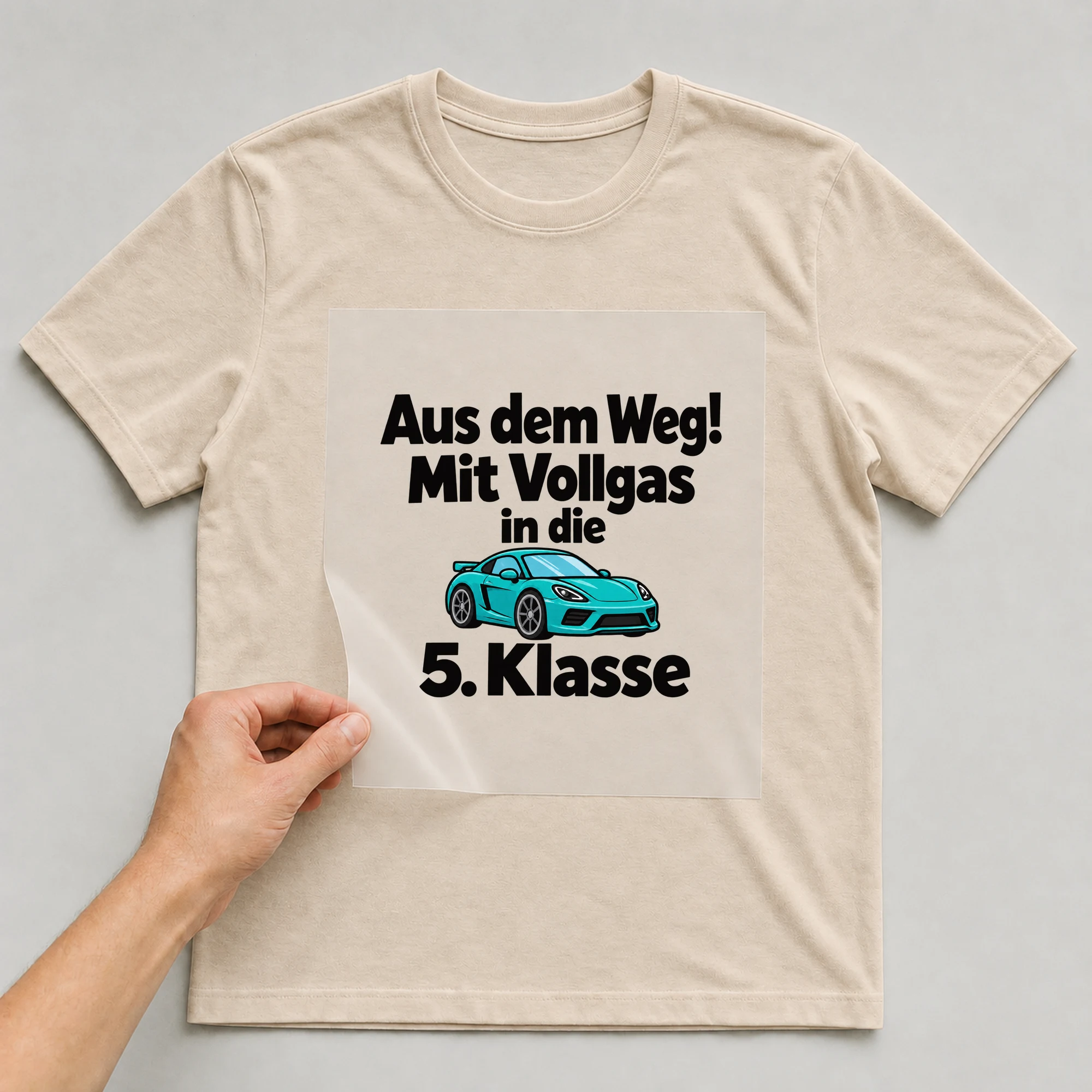 Bügelbild „Aus dem Weg! Mit Vollgas in die 5. Klasse“ auf beigem T-Shirt, Folie wird aufgelegt