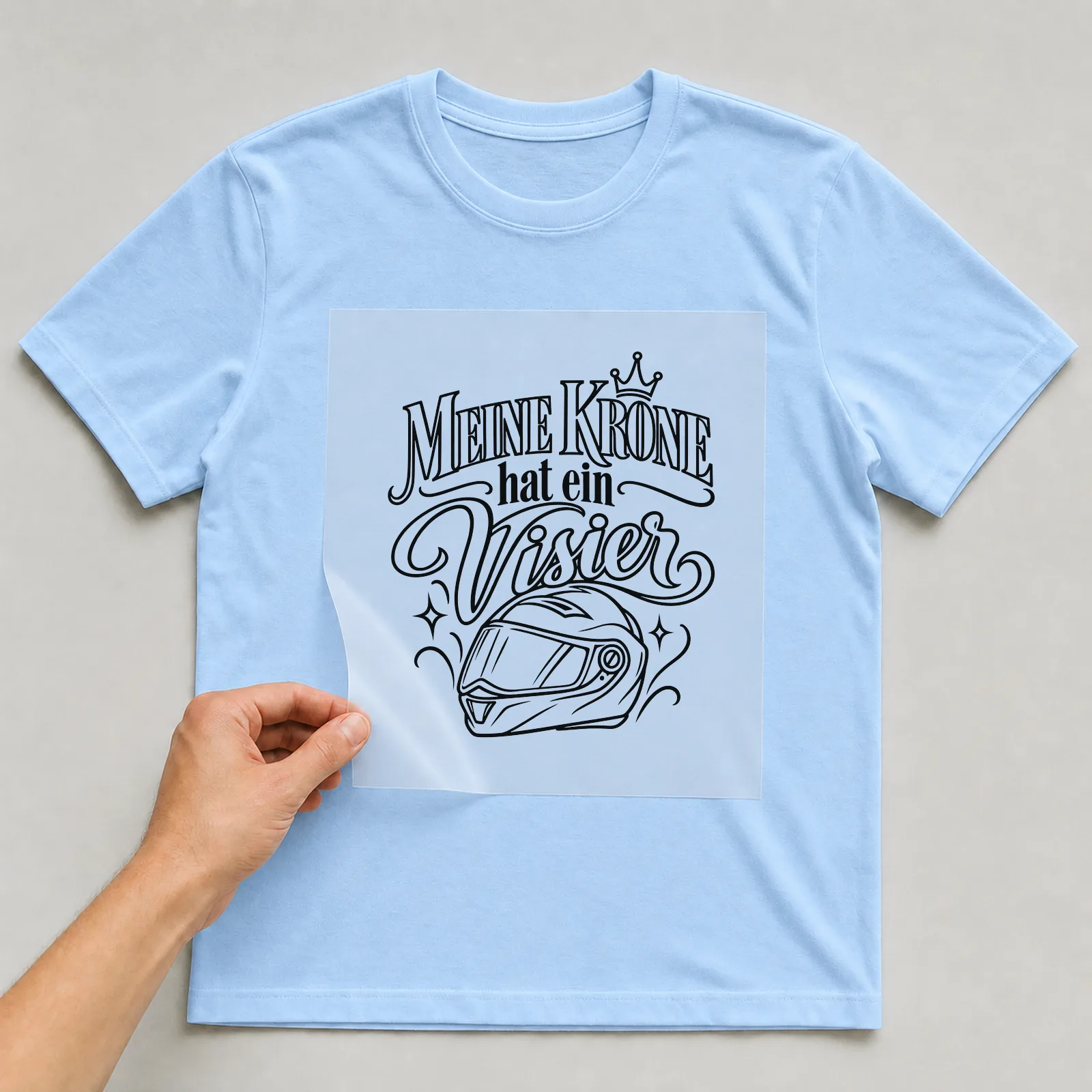 Bügelbild „Meine Krone hat ein Visier“ auf hellblauem T-Shirt, Folie wird aufgelegt