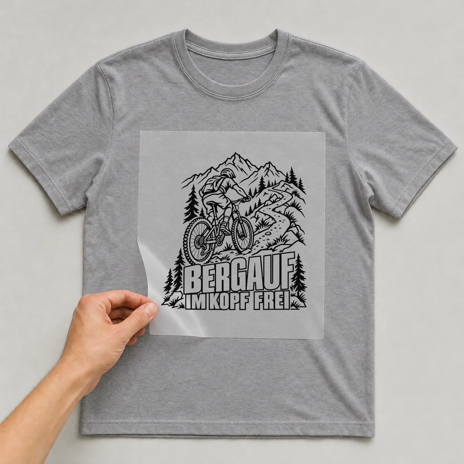 Bügelbild „Bergauf im Kopf frei“ auf grauem T-Shirt, Folie wird aufgelegt