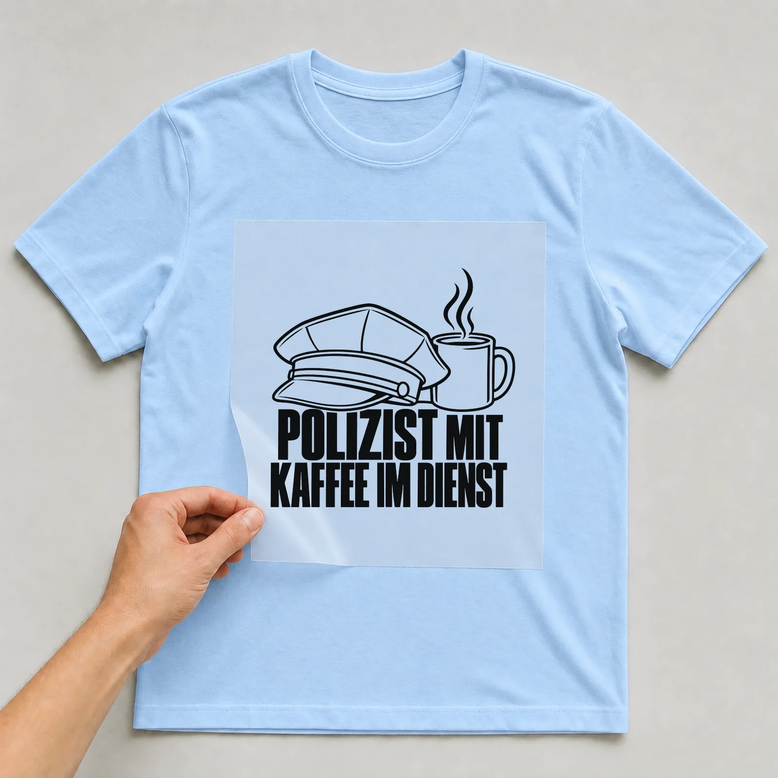 Bügelbild „Polizist mit Kaffee im Dienst“ auf hellblauem T-Shirt, Folie wird aufgelegt