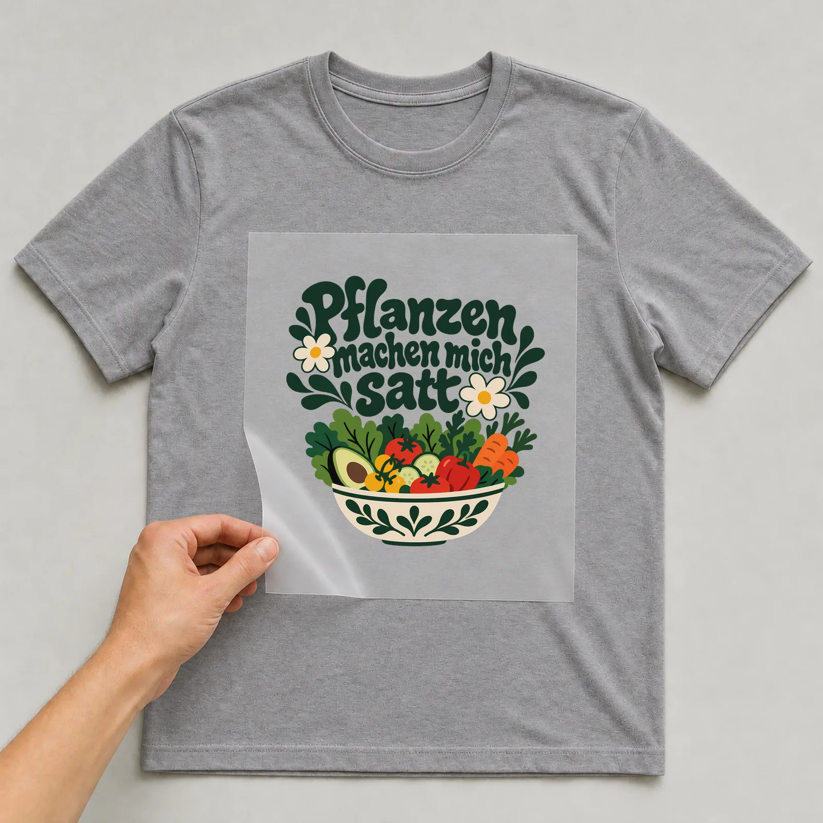 Bügelbild „Pflanzen machen mich satt“ auf grauem T-Shirt, Folie wird aufgelegt