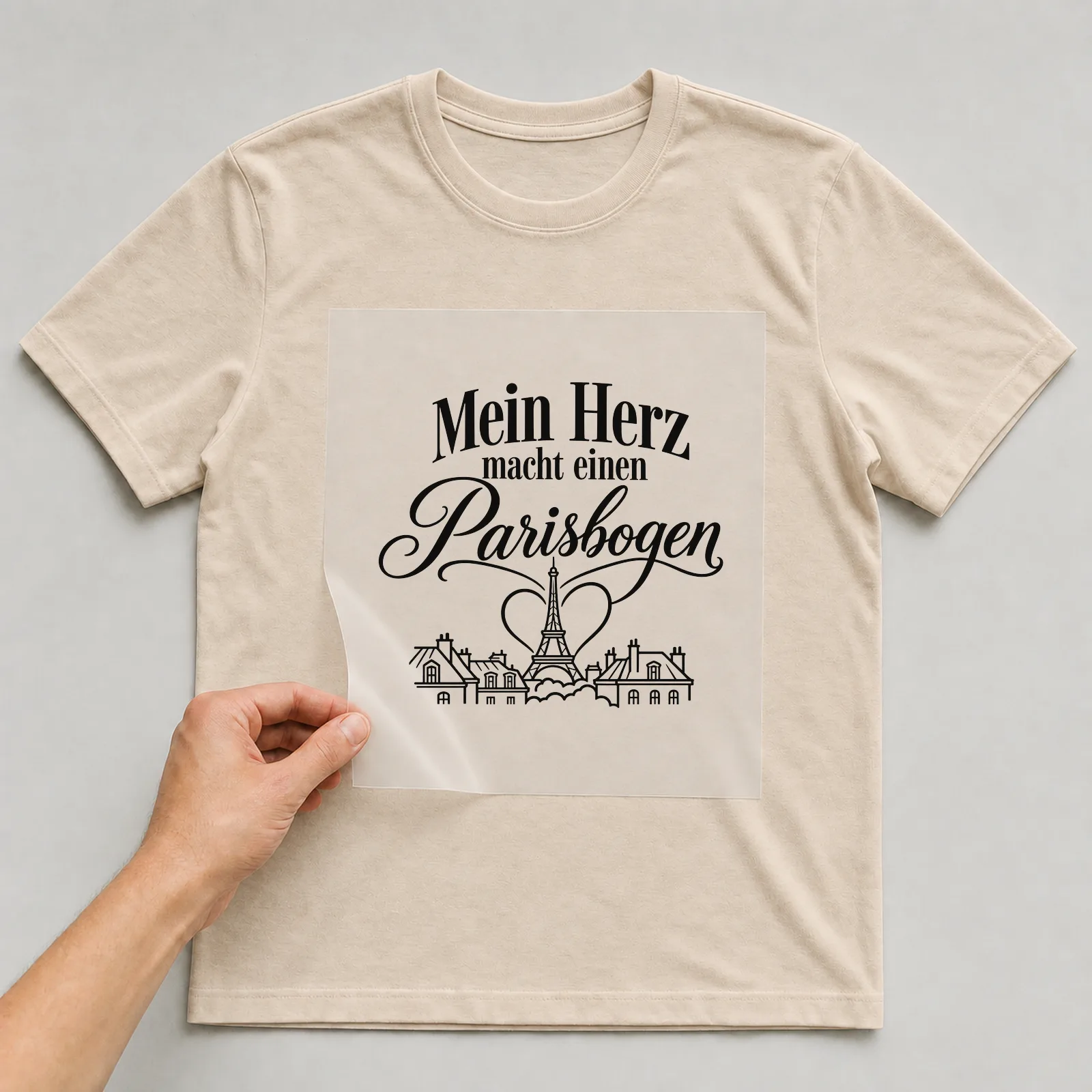 Bügelbild „Mein Herz macht einen Parisbogen“ auf beigem T-Shirt, Folie wird aufgelegt