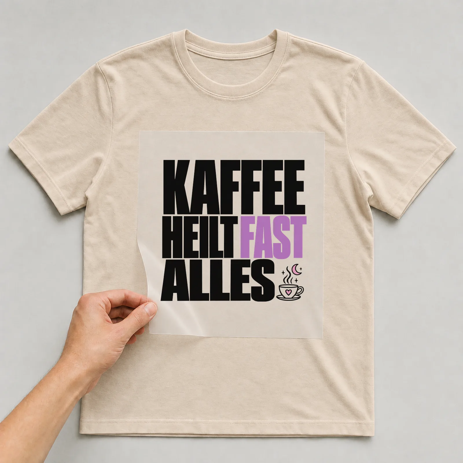 Bügelbild „Kaffee heilt fast alles“ auf beigem T-Shirt, Folie wird aufgelegt