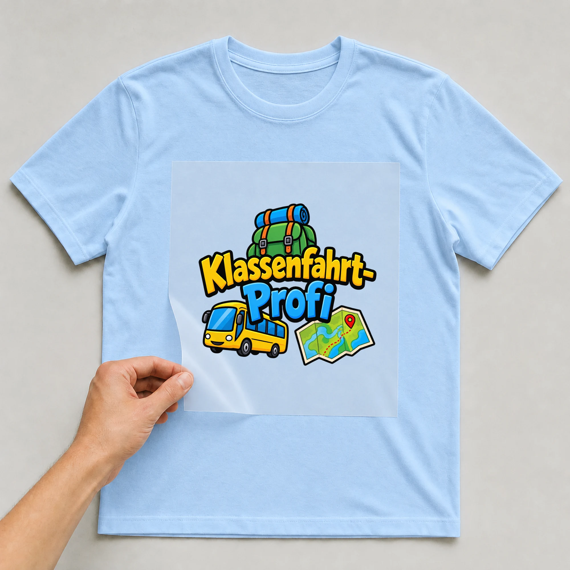 Bügelbild „Klassenfahrt-Profi“ auf babyblauem T-Shirt, Folie wird aufgelegt