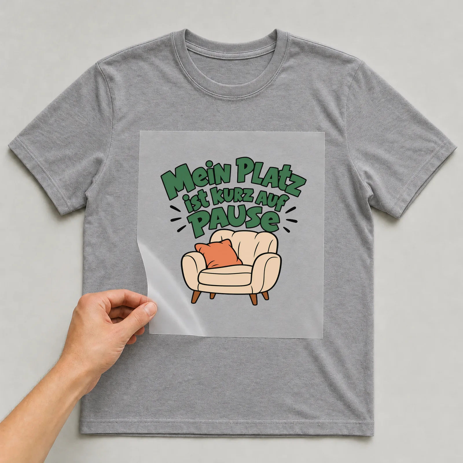 Bügelbild „Mein Platz ist kurz auf Pause“ auf grauem T-Shirt, Folie wird aufgelegt