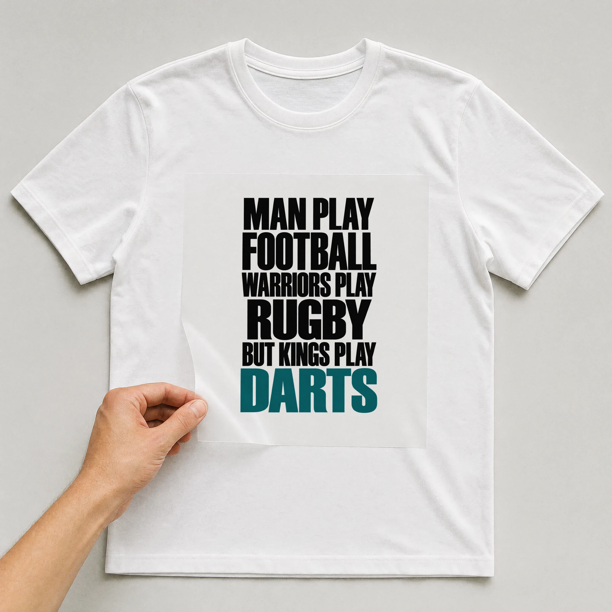 Bügelbild „Man Play Football Warriors Play Rugby But Kings Play Darts“ auf weißem T-Shirt, Folie wird aufgelegt