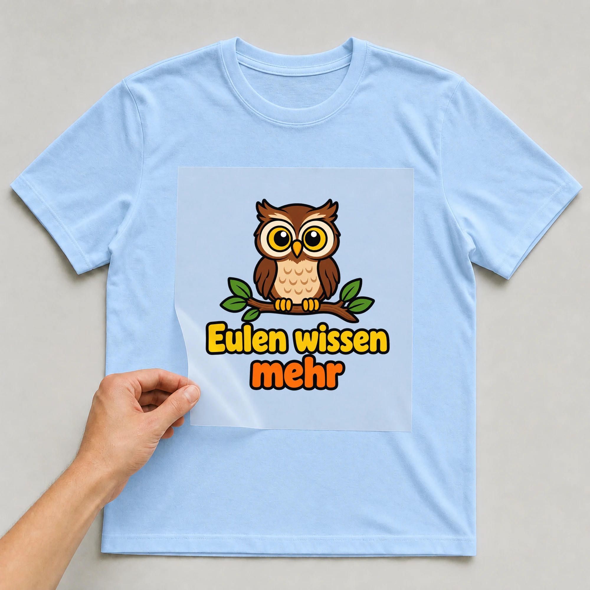 Bügelbild „Eulen wissen mehr“ auf babyblauem T-Shirt, Folie wird aufgelegt