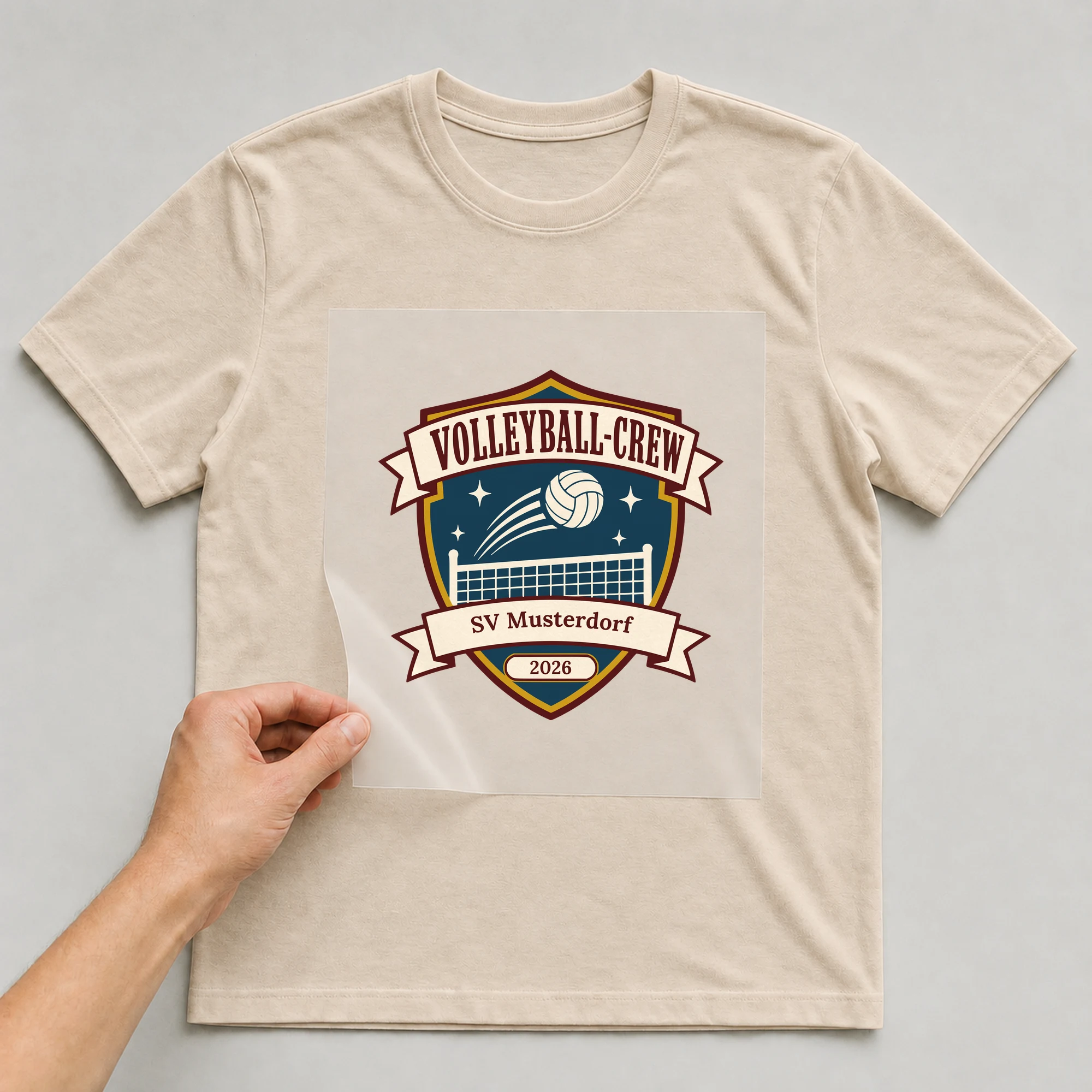 Bügelbild Volleyball-Crew mit Verein und Jahr auf beigem T-Shirt, Folie wird aufgelegt