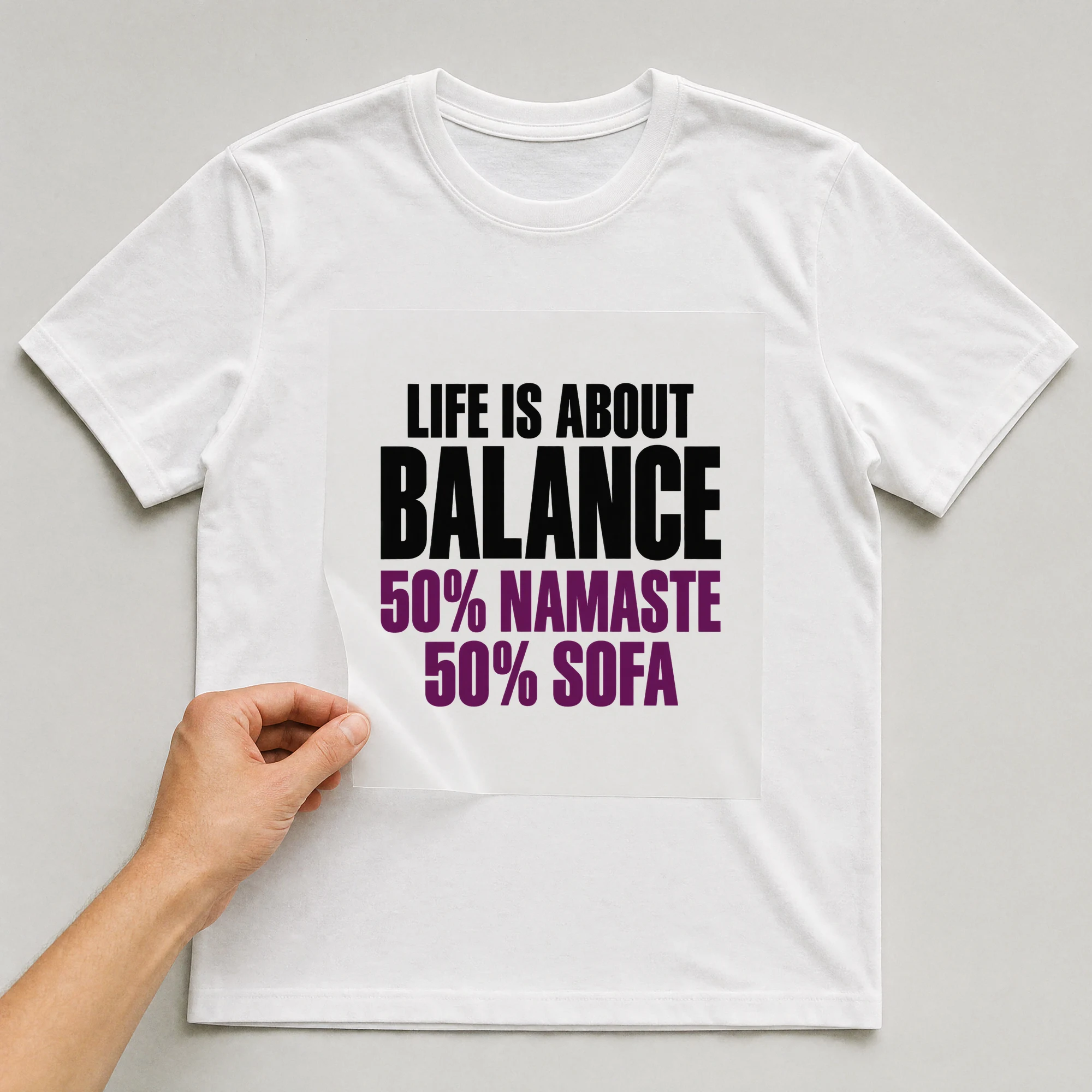 Bügelbild „Life is about balance: 50% Namaste, 50% Sofa“ auf weißem T-Shirt, Folie wird aufgelegt